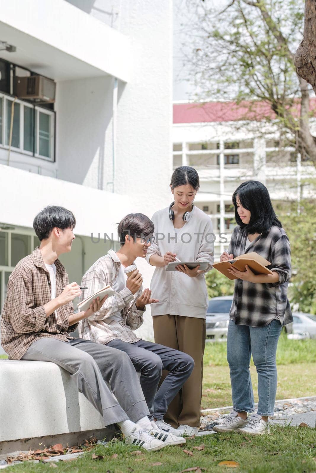 Group of Asian college student reading books and tutoring special class for exam on grass field at outdoors. Happiness and Education learning concept. Back to school concept. Teen and people theme...