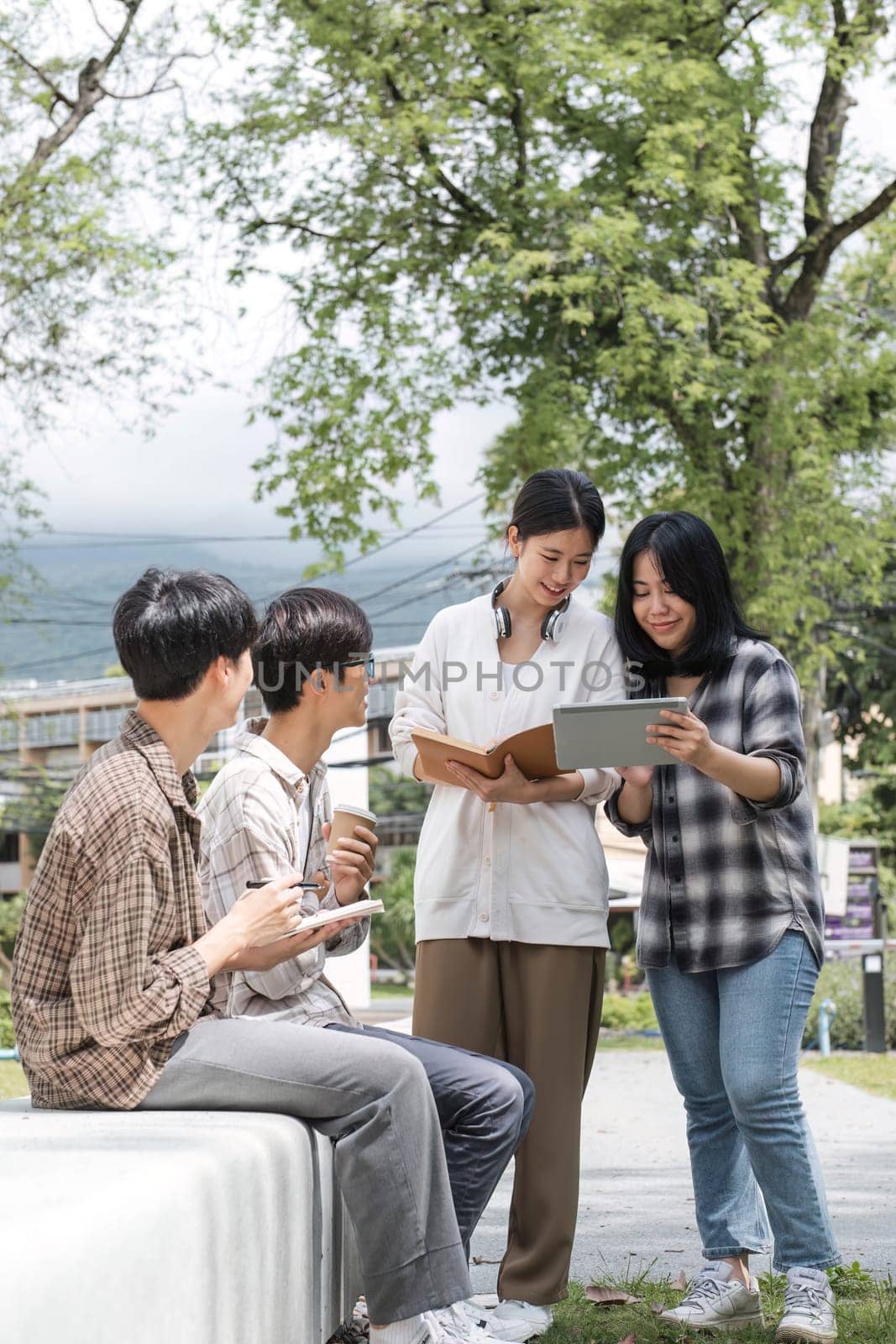Group of Asian college student reading books and tutoring special class for exam on grass field at outdoors. Happiness and Education learning concept. Back to school concept. Teen and people theme. by wichayada