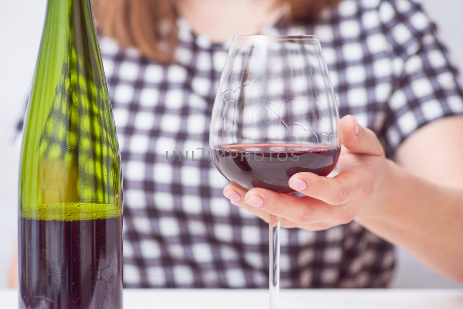 A woman with glass red wine. A woman is drinking red wine.