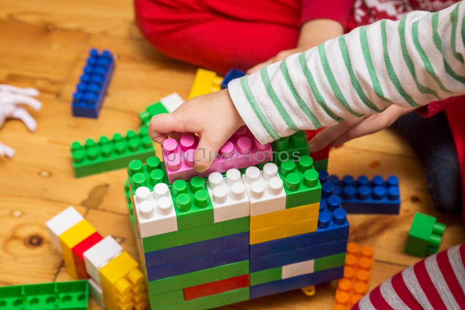 A child isplaying with toy building blocks. A kid is having fun and building out of bright constructor bricks