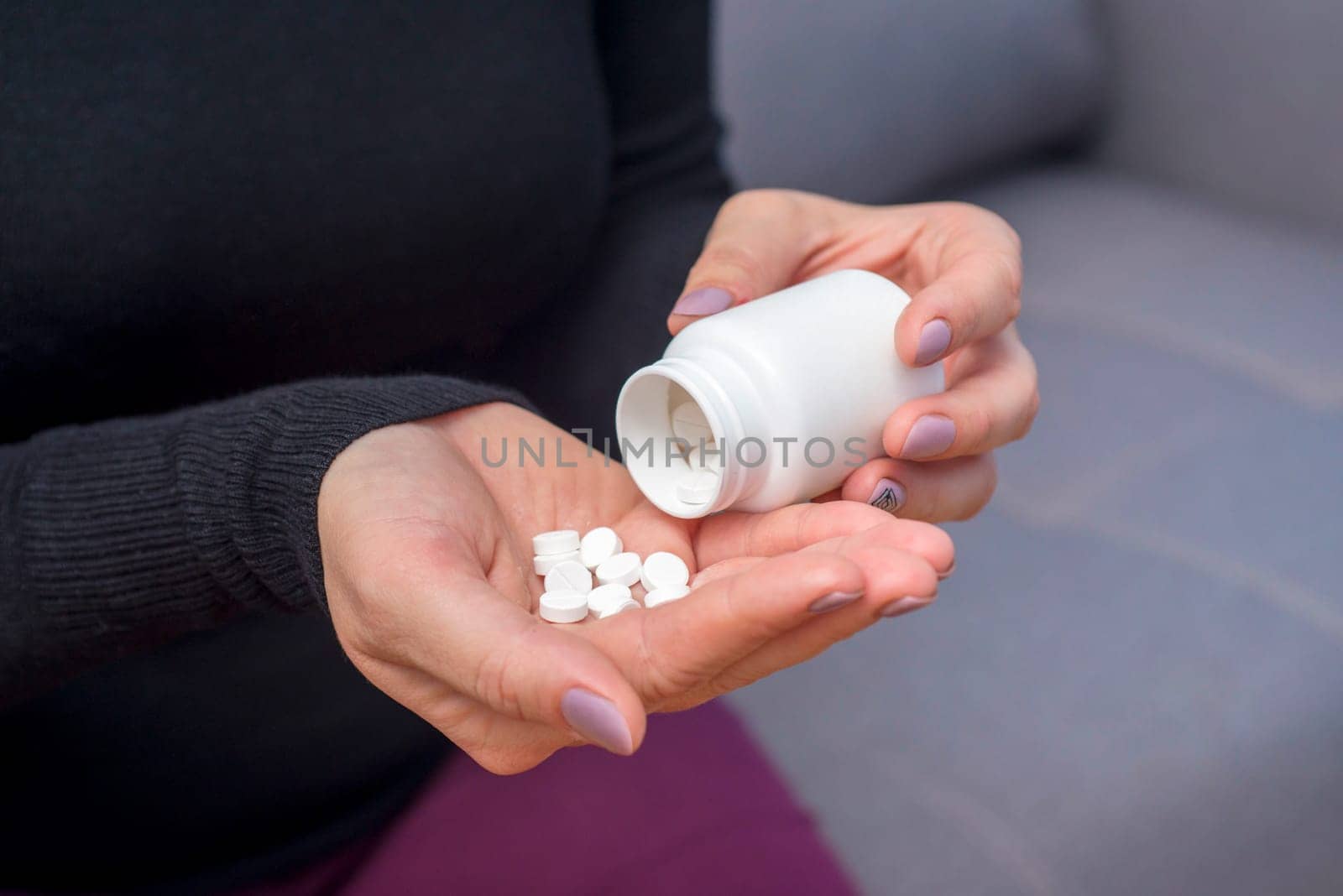 A woman spilling out white the pills from a bottle container to her hand. A woman pouring pills from prescription pill bottle.