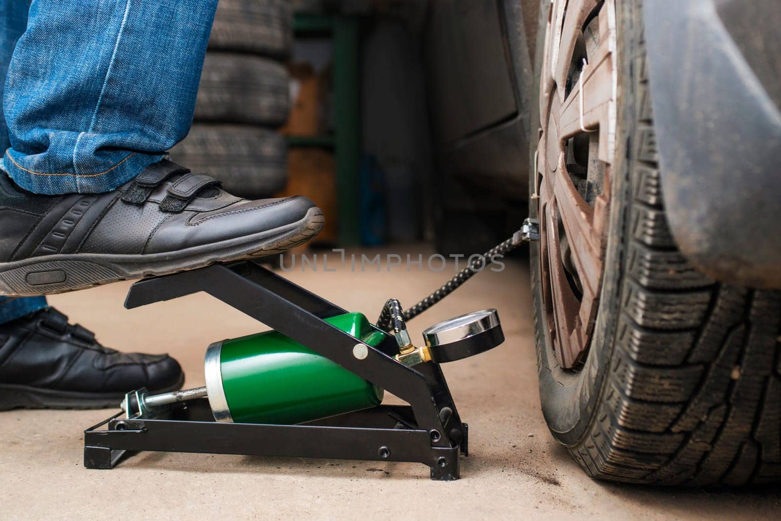 Auto mechanic tightening the nuts with a wheel wrench. Seasonal tire change. Car service concept