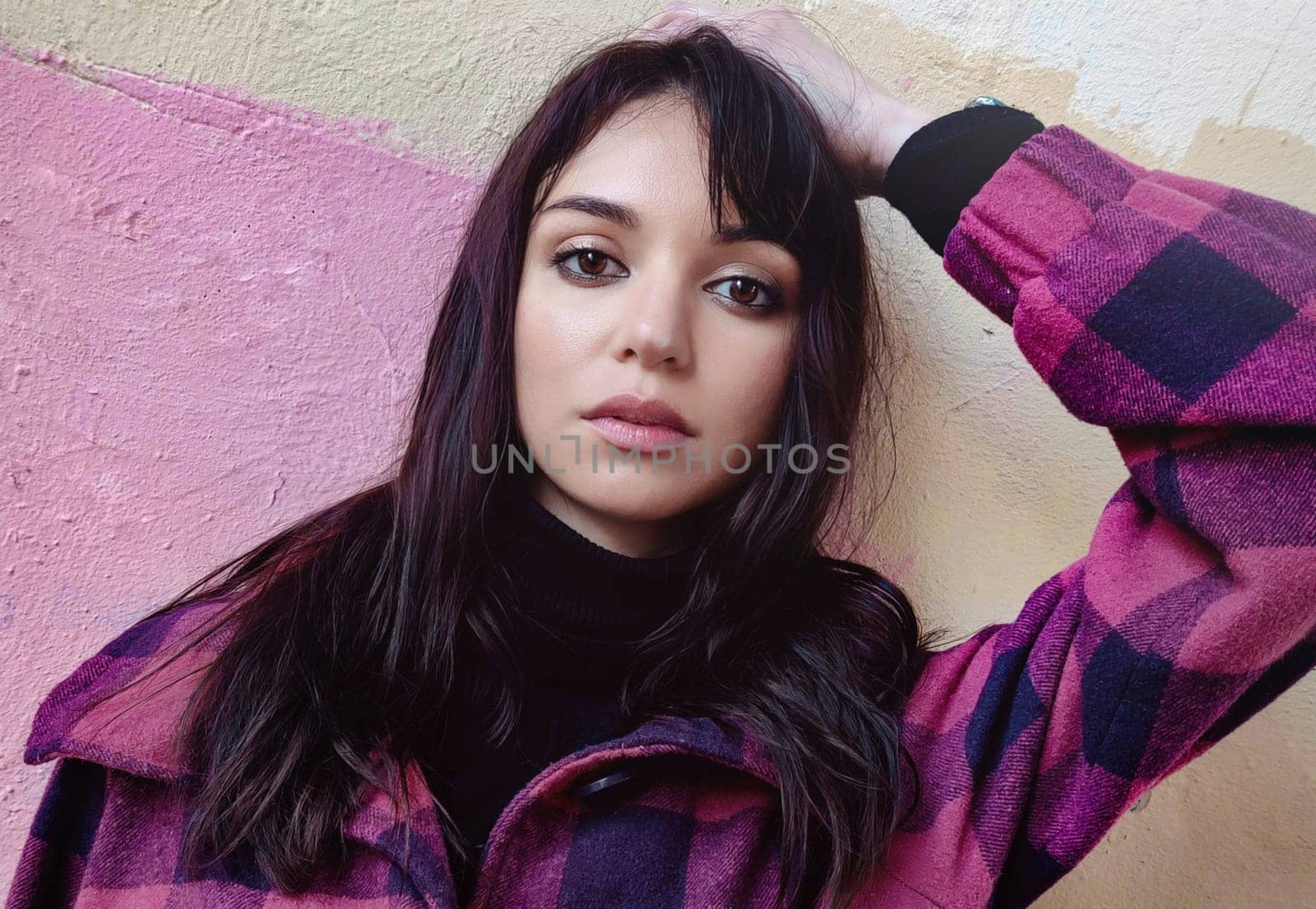 Woman with dark hair in a black golf with a serious face put her hand behind her head by Nickstock