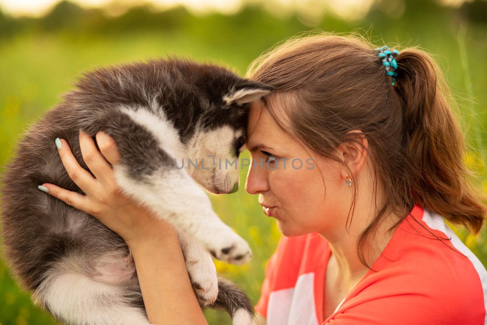 Beautiful young caucasian woman is playing with her puppy dog outdoor. Animal, friendship, people and love concept.