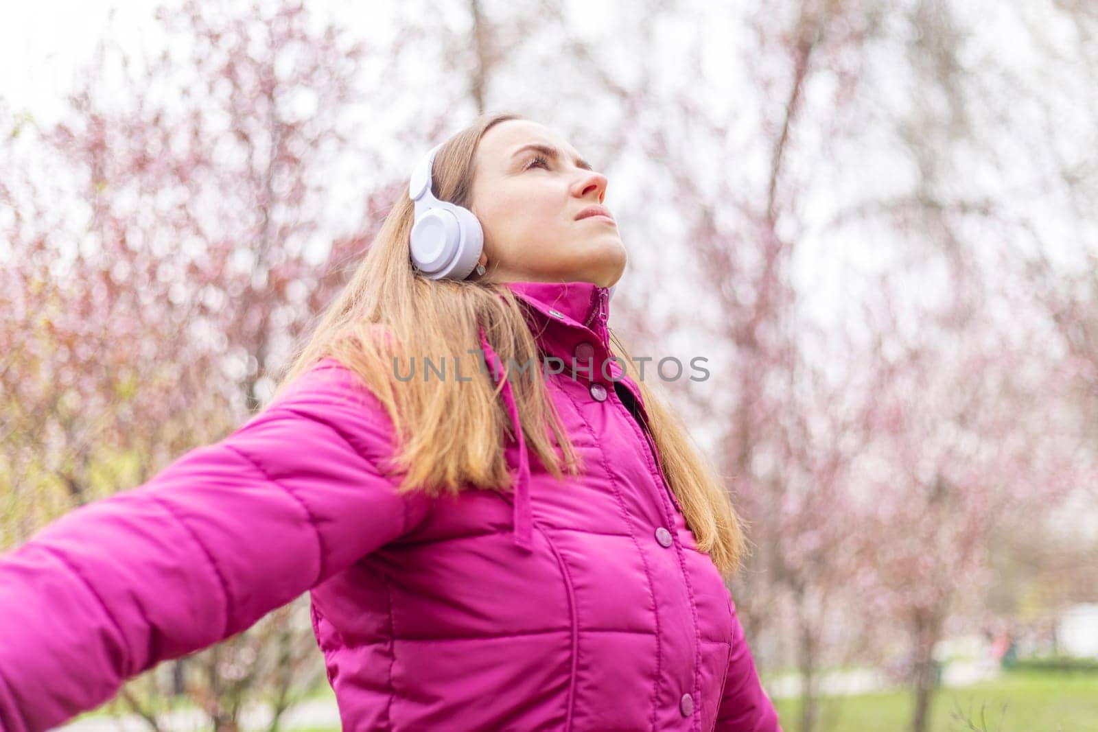 Relaxed woman wearing headphones breathing fresh air listening to music in a forest or park