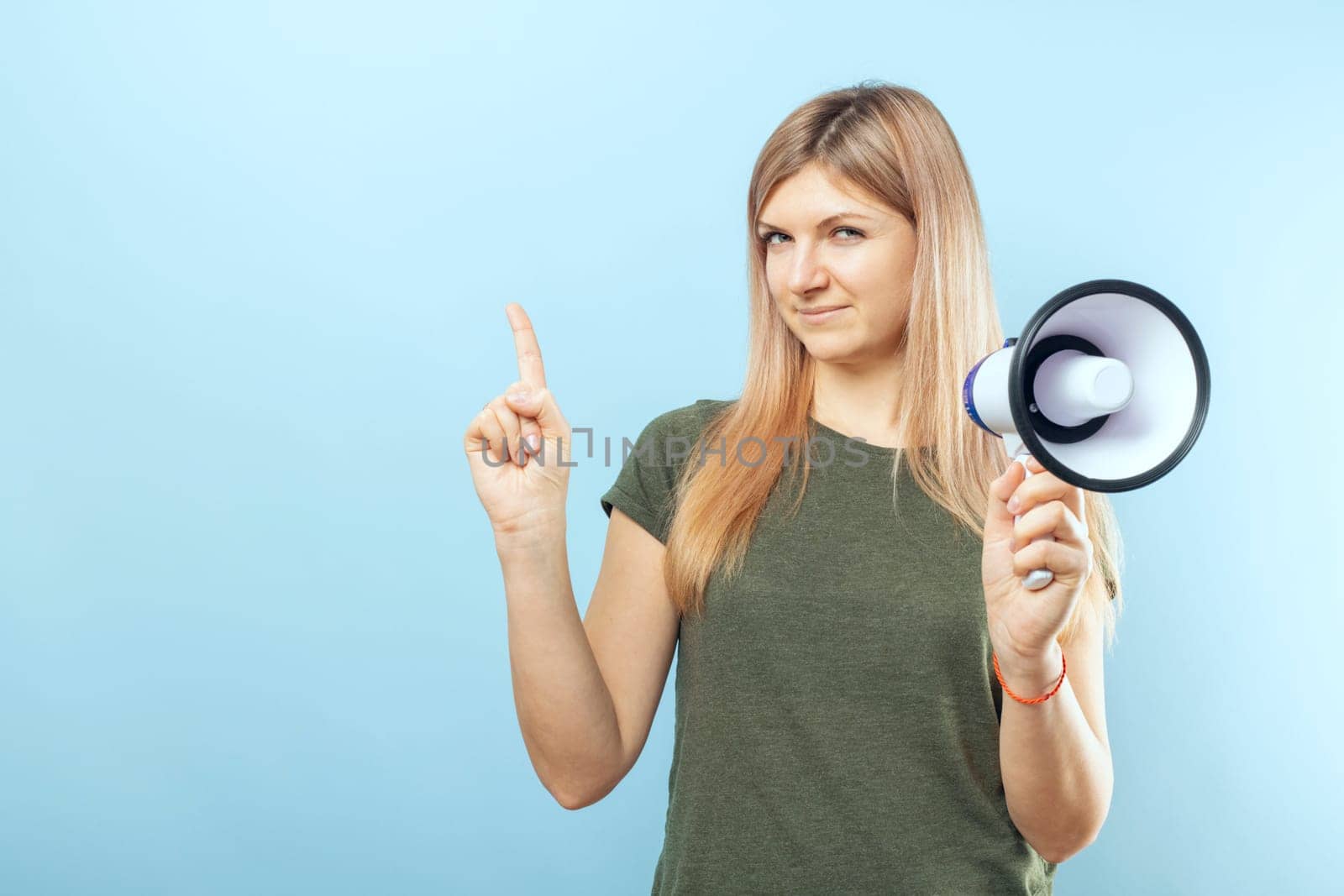 Young woman holding megaphone on blue background. Concept of speech and announce, idea for marketing or sales.