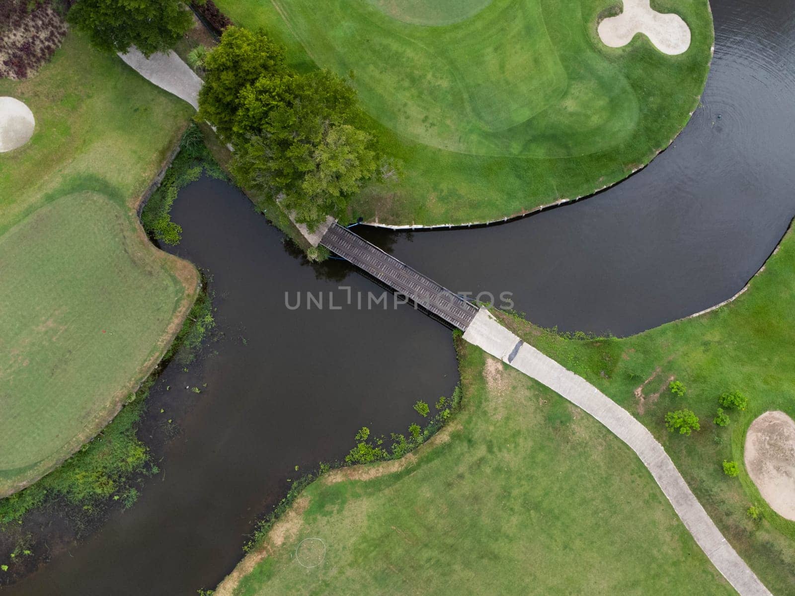 Aerial view of golf course with a rich green turf beautiful scenery. Sand bunkers at a beautiful golf course by the pond.