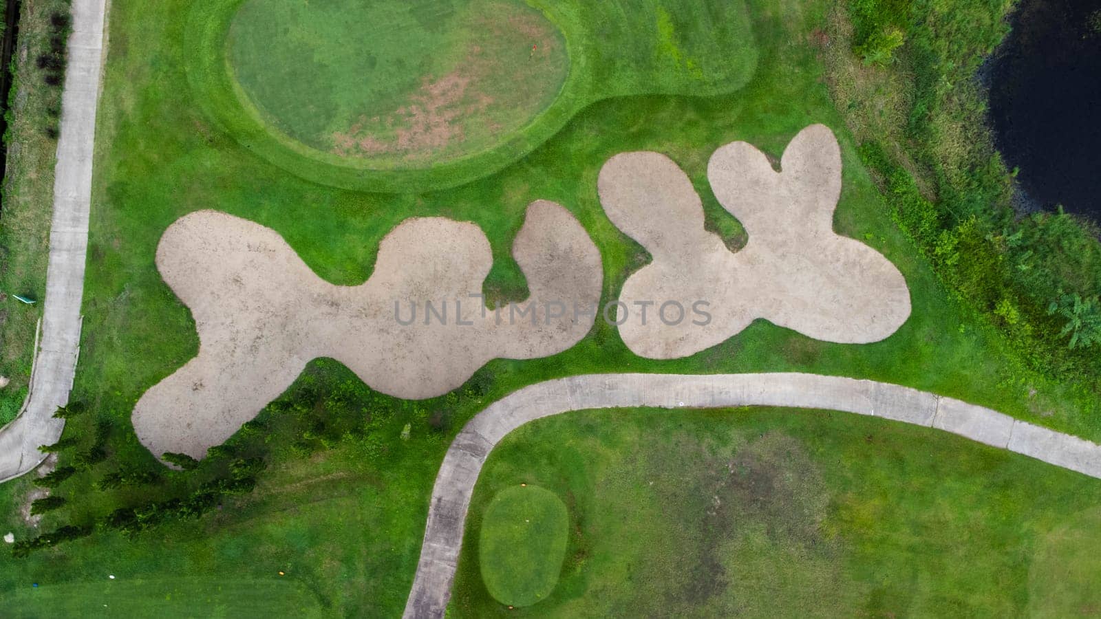 Aerial view of golf course with a rich green turf beautiful scenery. Sand bunkers at a beautiful golf course by the pond.