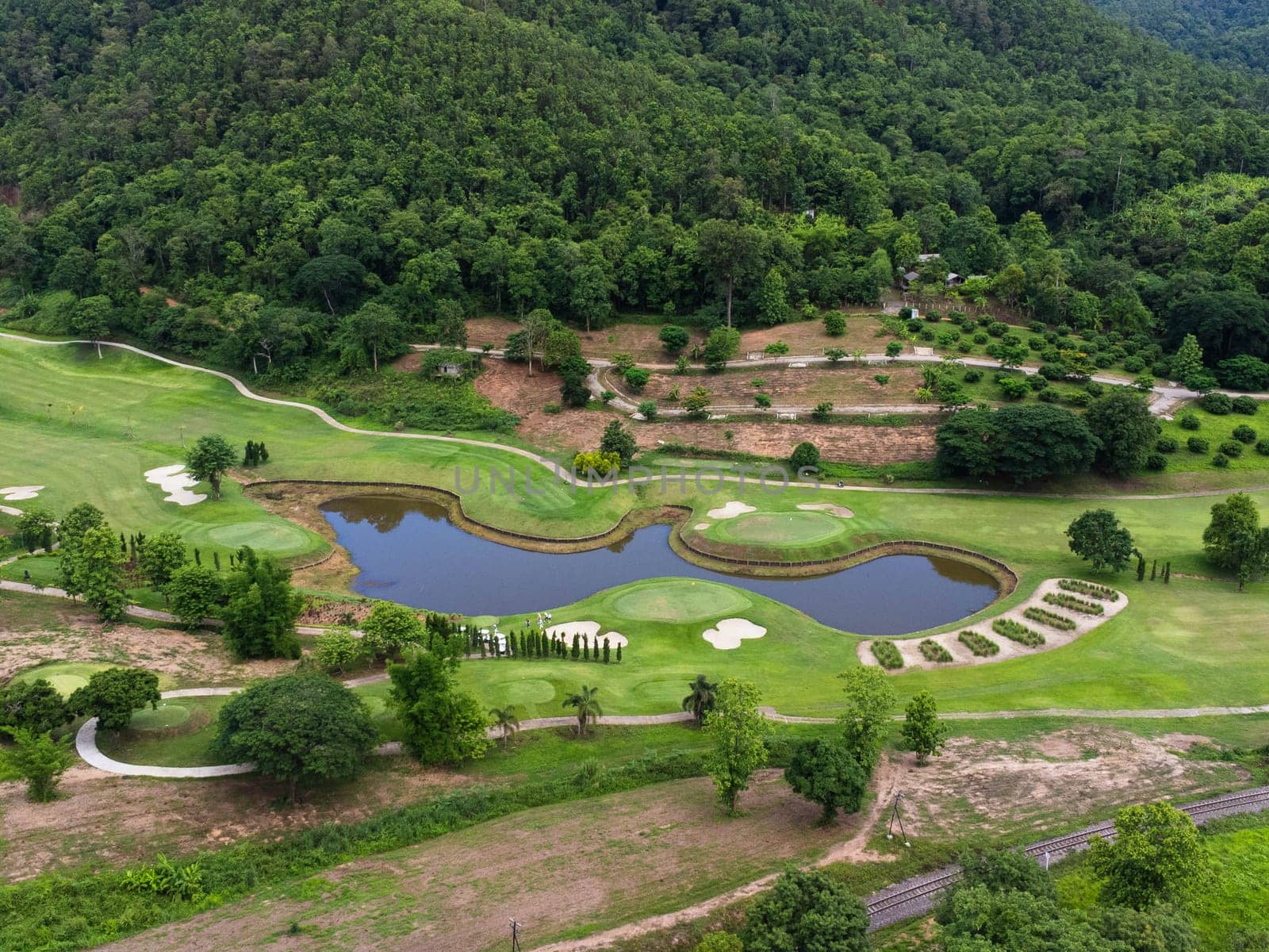 Aerial view of golf course with a rich green turf beautiful scenery. Sand bunkers at a beautiful golf course by the pond.