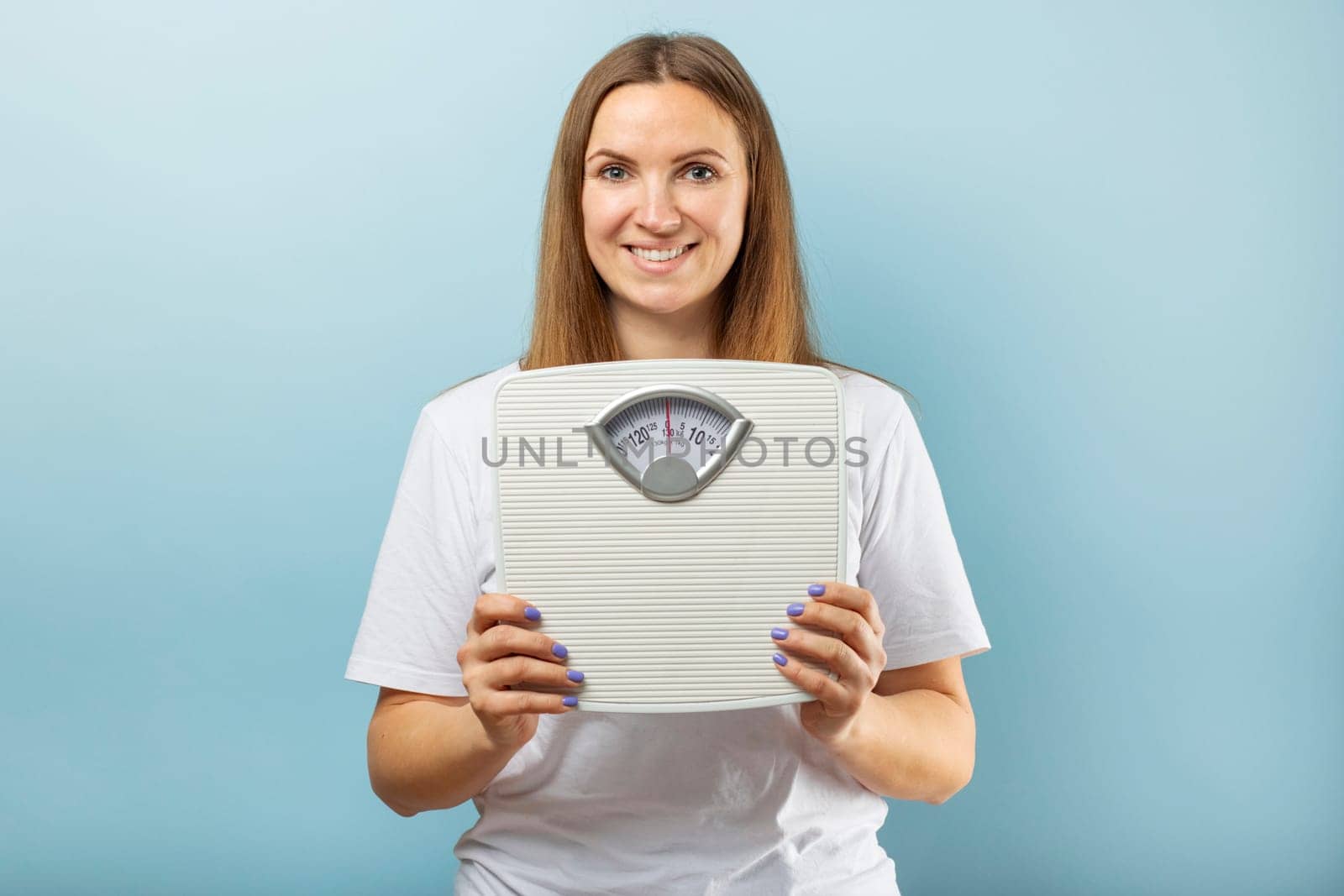 Young woman holding white scales to check the results of her diet . Diet and sport concept.