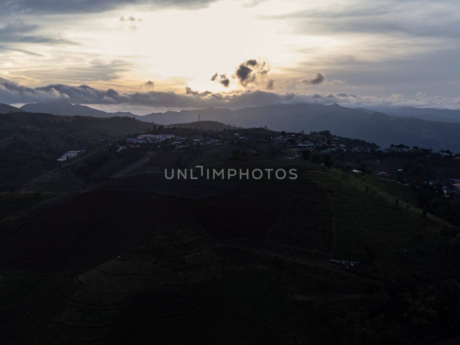 Aerial view of beautiful sunrise or sunset sky and rural villages. Village landscape in misty valley and mountain clouds in thailand. by TEERASAK