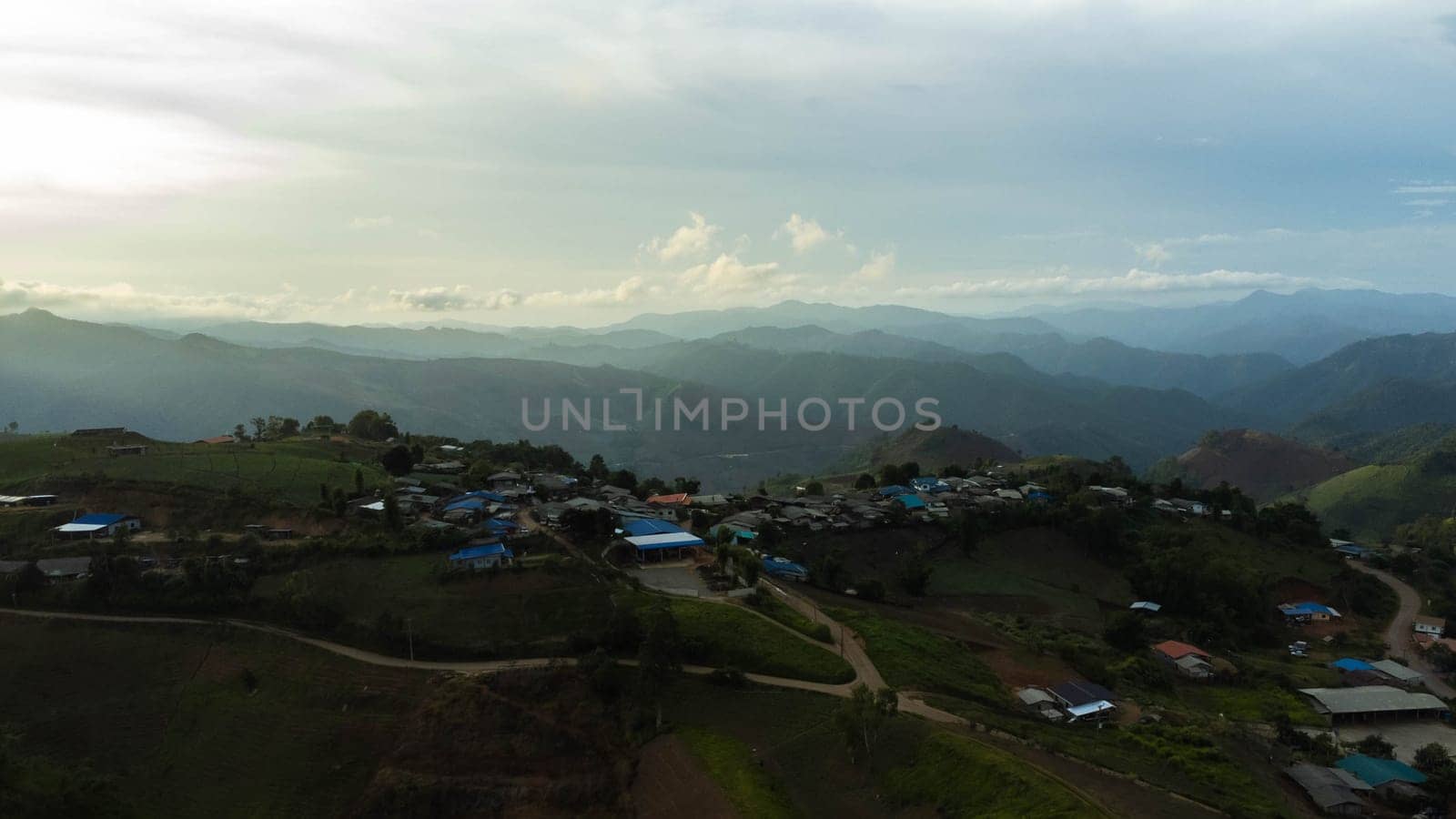 Aerial view of beautiful sunrise or sunset sky and rural villages. Village landscape in misty valley and mountain clouds in thailand. by TEERASAK