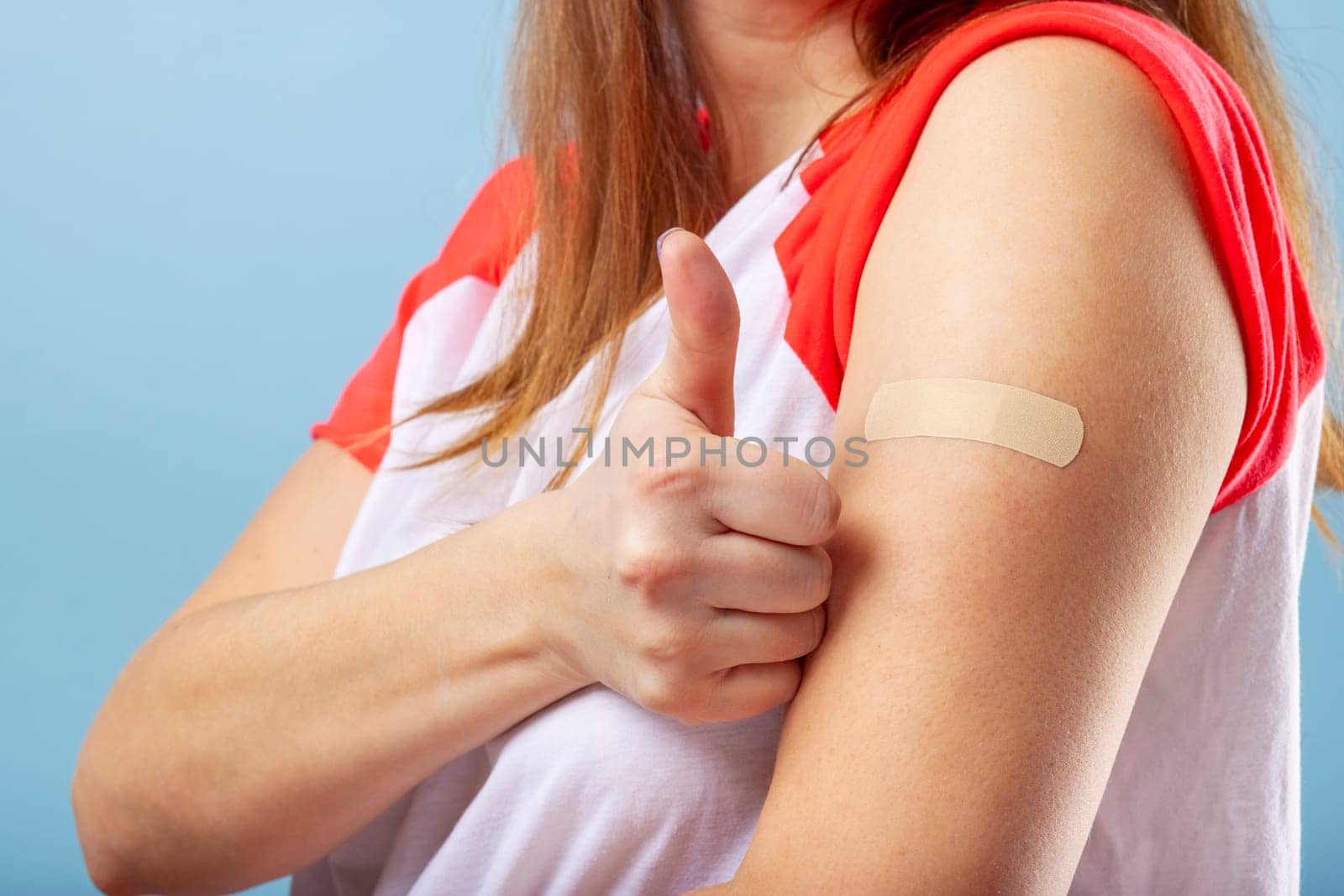 Vaccination COVID-19. Vaccinated woman gesturing with thumbs up showing hand with plaster cast after injection of coronavirus vaccine. Successful Covid-19 vaccination.