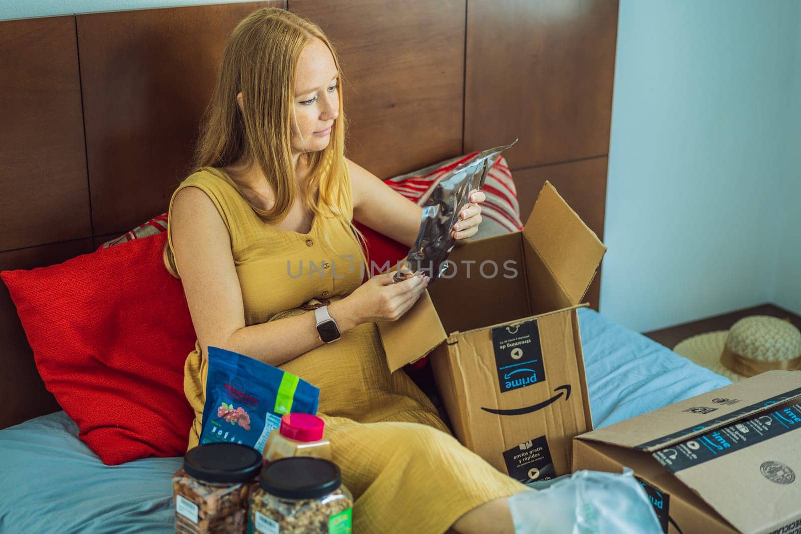 12.21.22, Mexico, Playa del Carmen: A pregnant woman received a package from Amazon. The woman pulls out the nuts she ordered from Amazon. Online shopping and healthy eating during pregnancy.