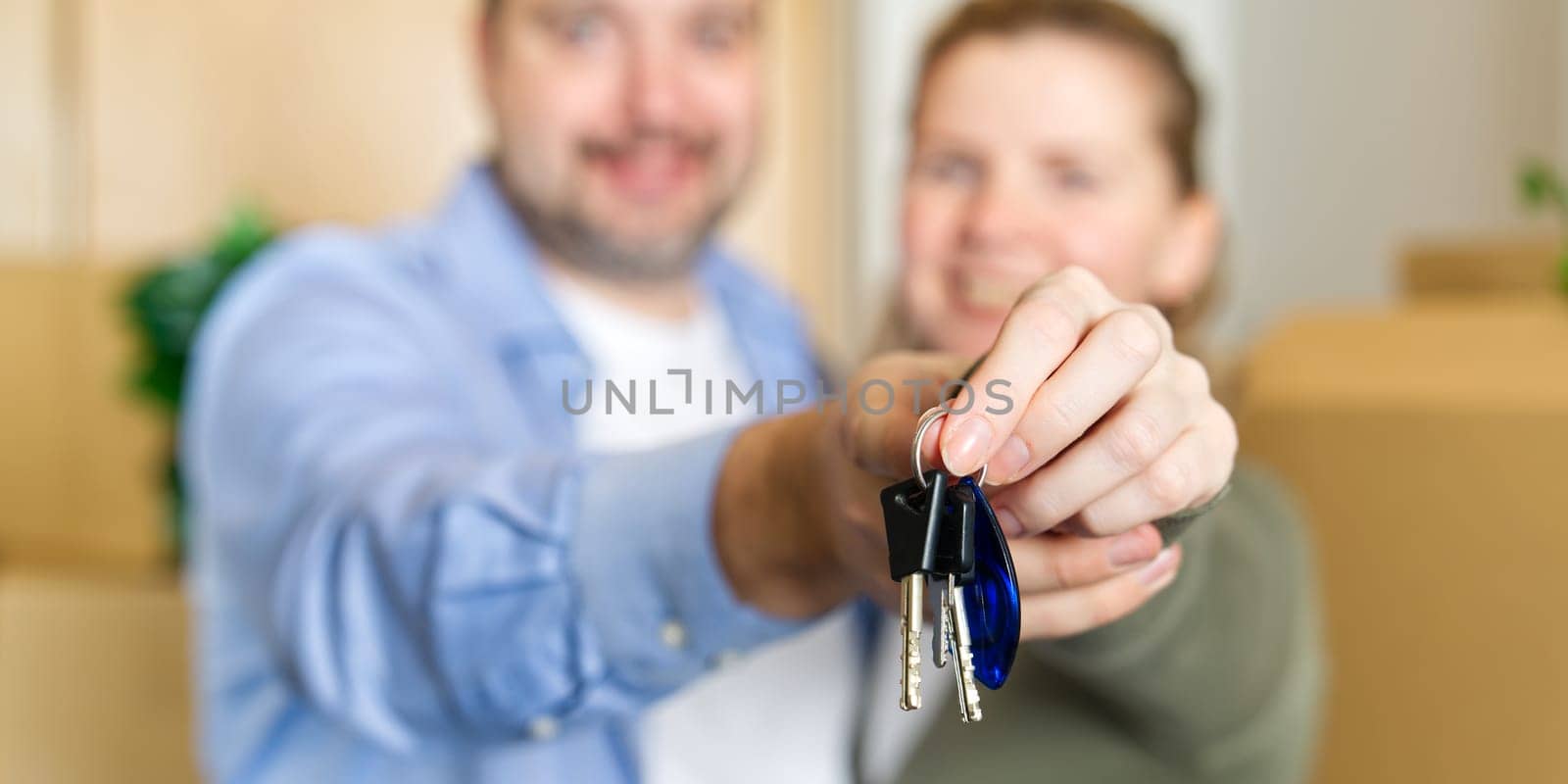 Couple showing keys to new apartment. real estate mortgage, loan concept. moving in new house. Young smiling couple holding their new house keys. first own apartment or house.