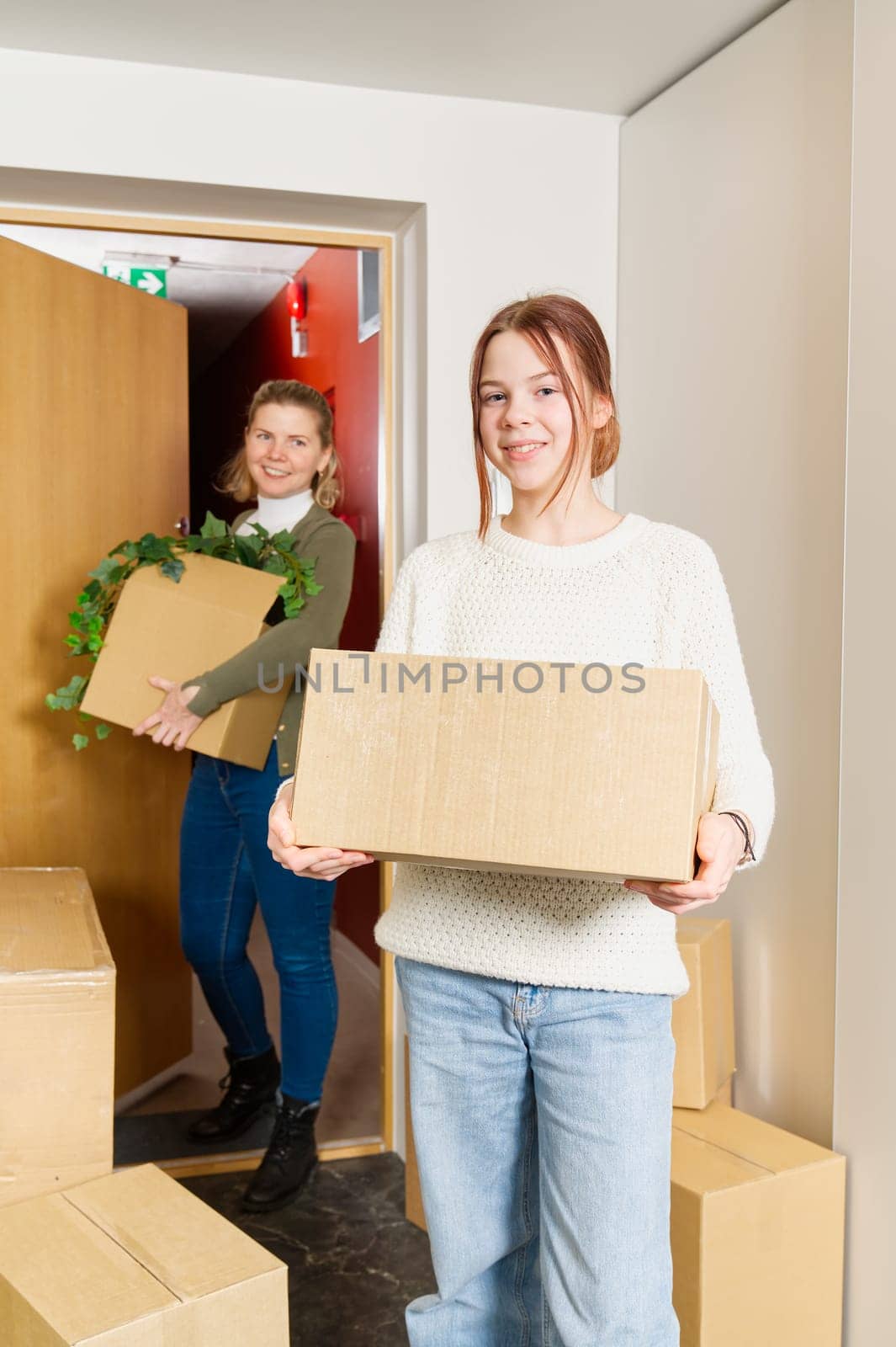 happy single mother with childrens moves to a new house. Moving day concept. children carry cardboard boxes when moving.