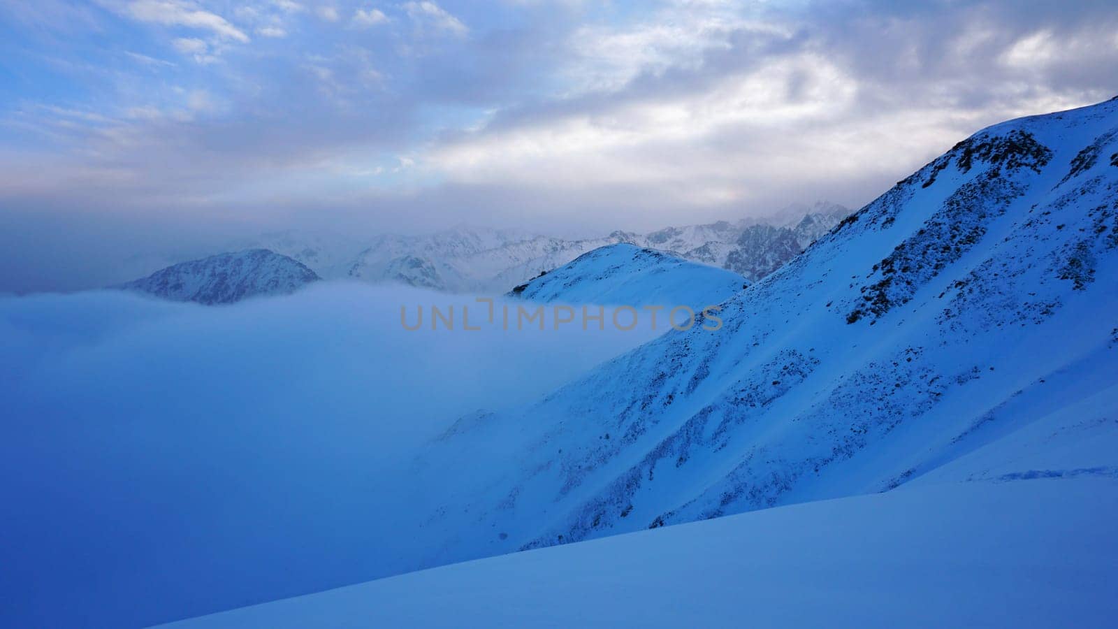 Ocean of clouds in snowy mountains at dawn by Passcal