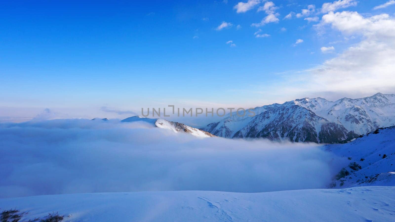 Ocean of clouds in snowy mountains at dawn by Passcal