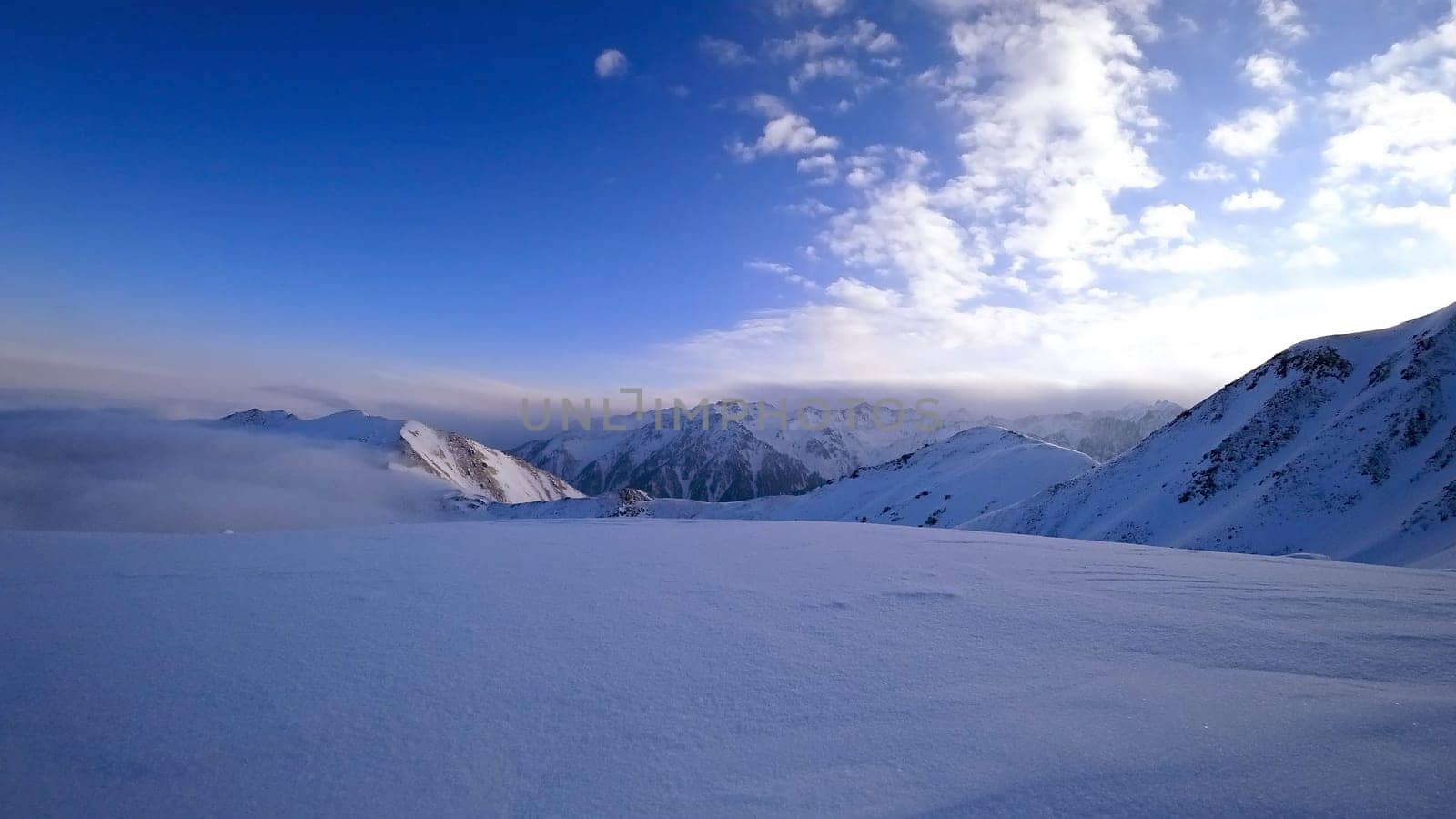 Ocean of clouds in snowy mountains at dawn by Passcal