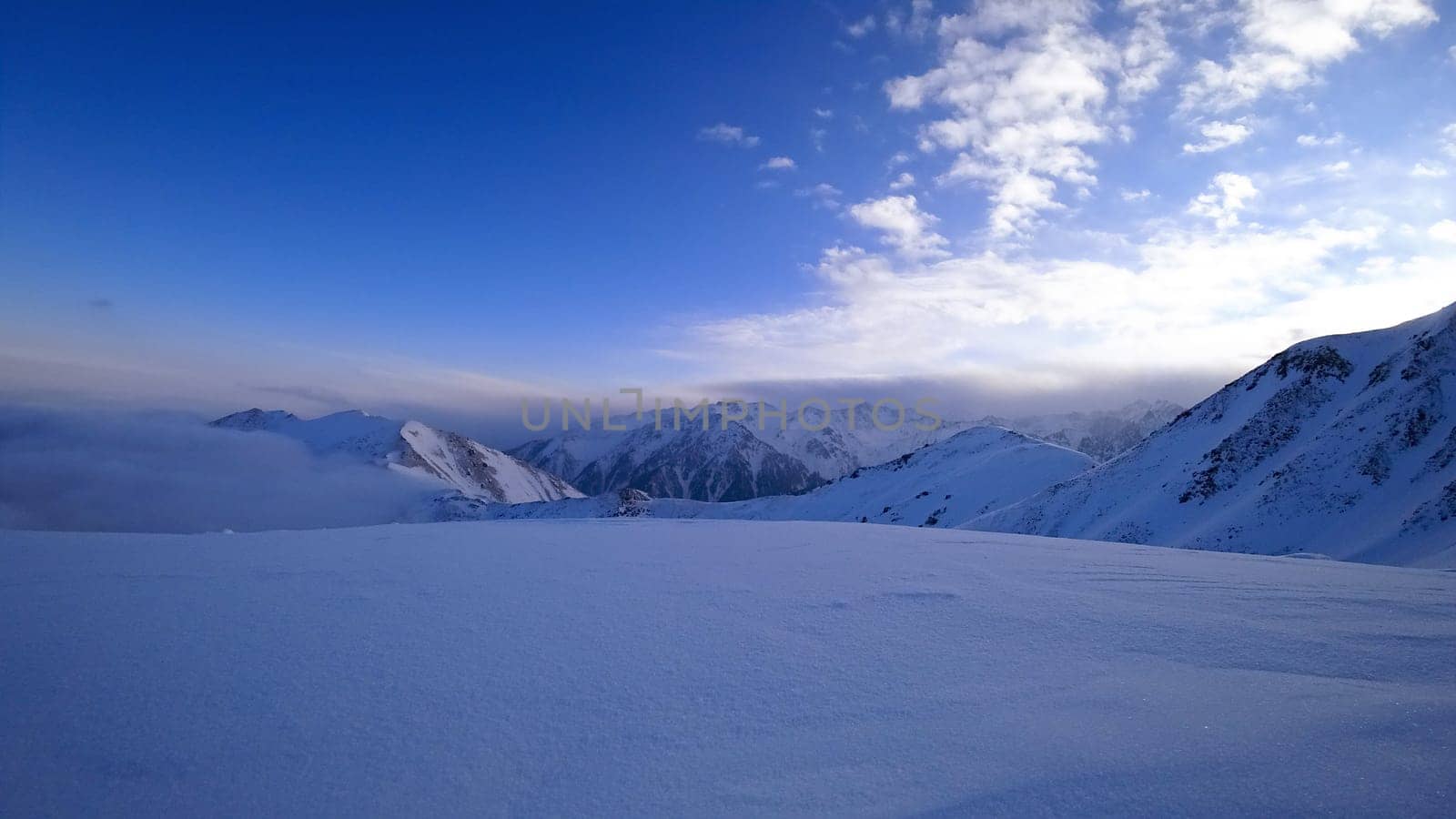 Ocean of clouds in snowy mountains at dawn by Passcal