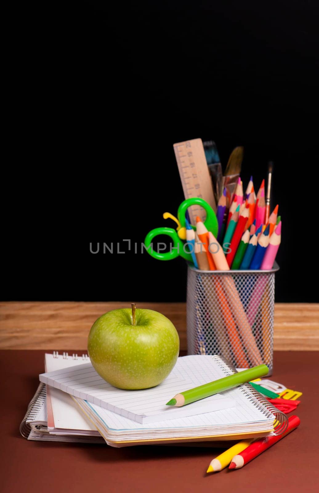 Magnifying glass, scissors, colored paper, textbooksboard, books, pencils, opened empty notebook against a dark background by aprilphoto