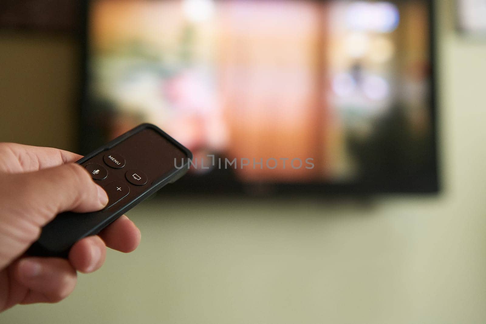 Multimedia streaming concept. Hand holding remote control. TV screen with lot of pictures. by snep_photo
