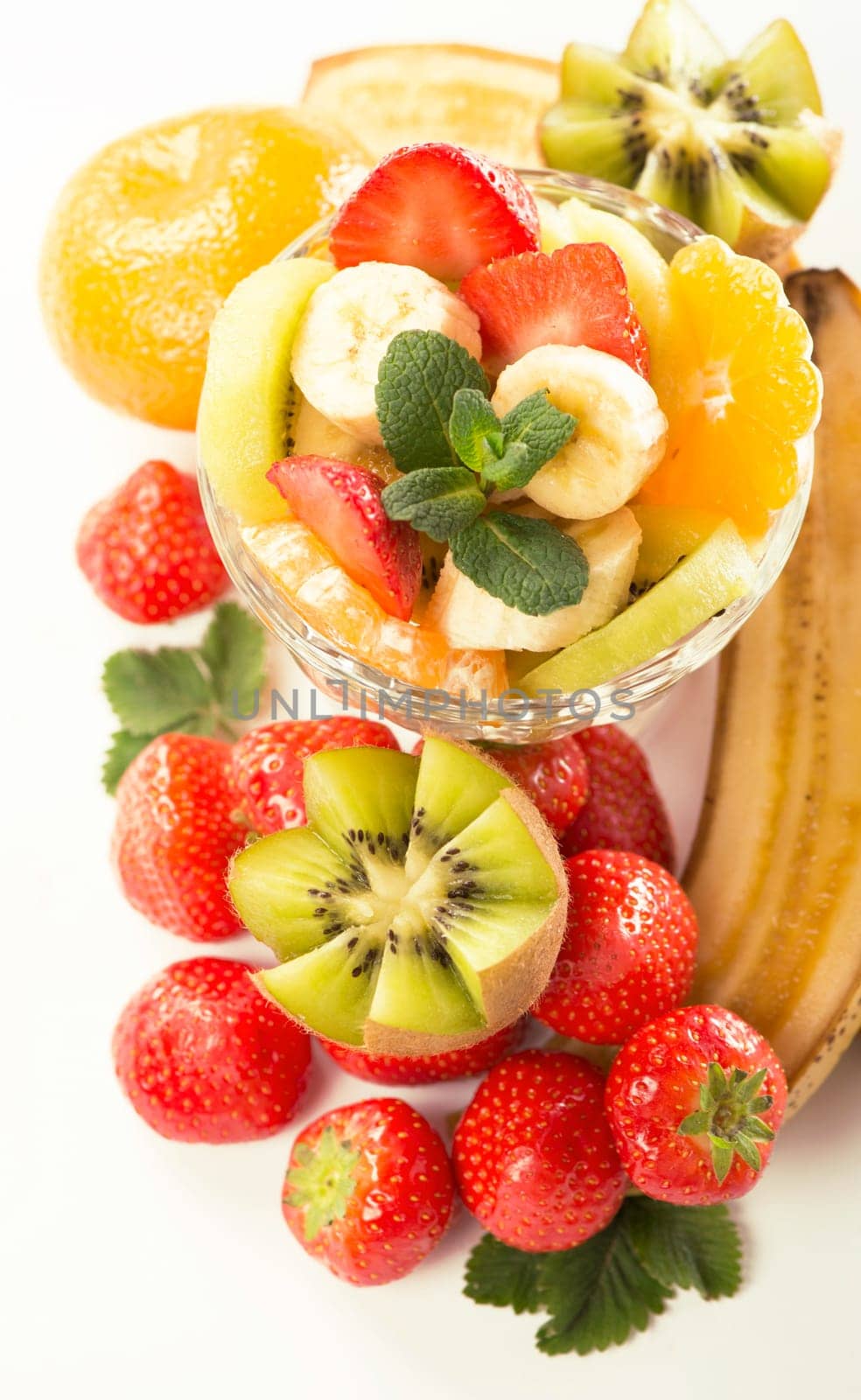 Bananas, kiwi and strawberry and glass bowl with fresh fruits salad close up