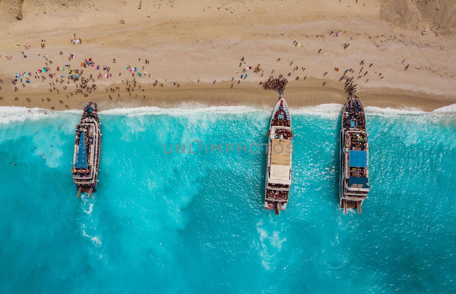 Aerial view of three tourist boats anchoring on the egremni beach with turquoise colored sea water.  