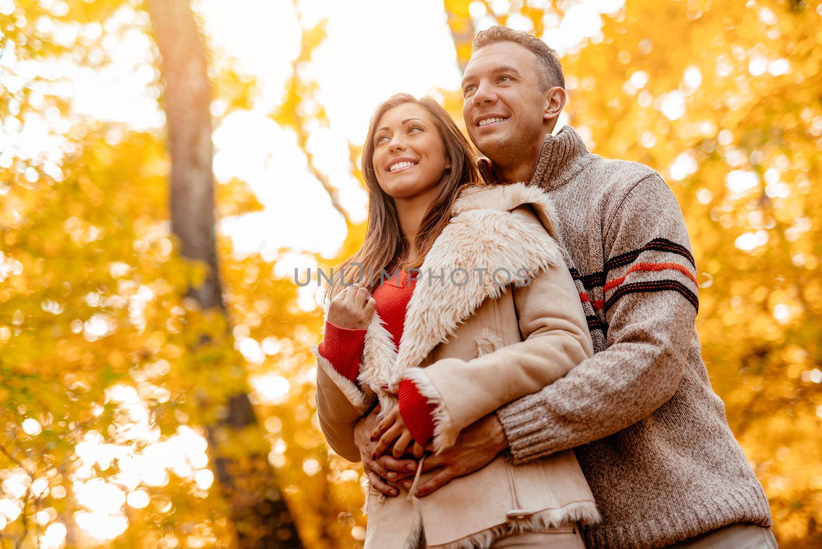 Beautiful smiling couple enjoying in sunny forest in autumn colors.