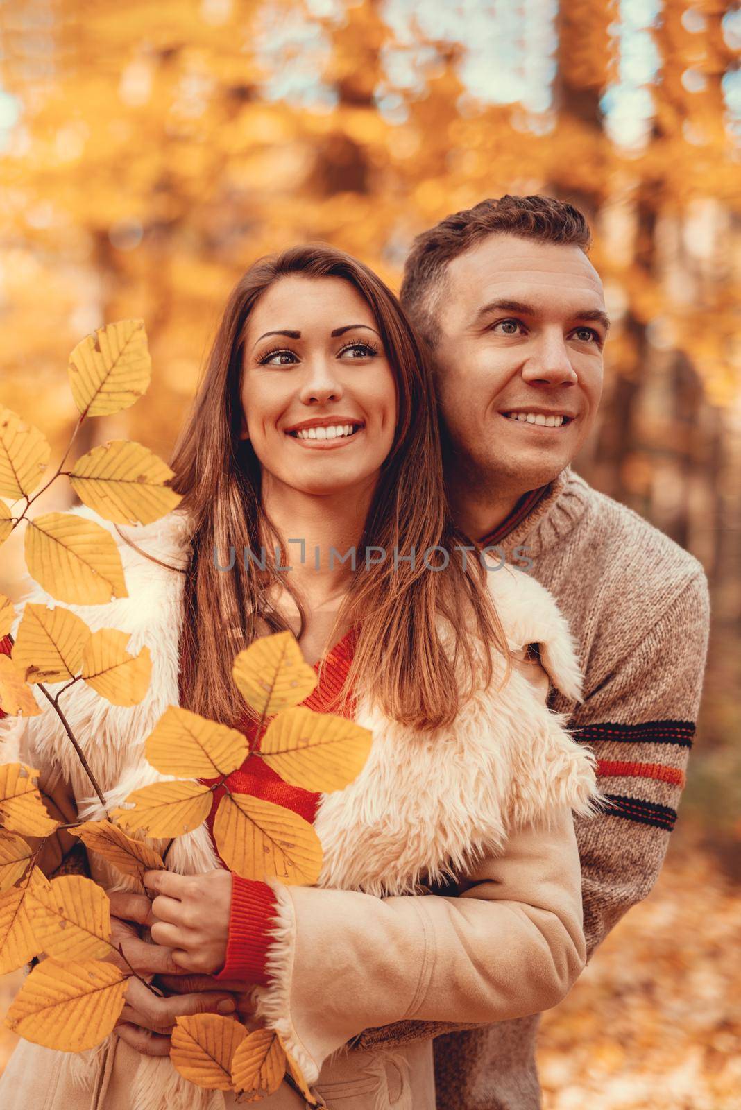 Beautiful smiling couple enjoying in sunny forest in autumn colors.