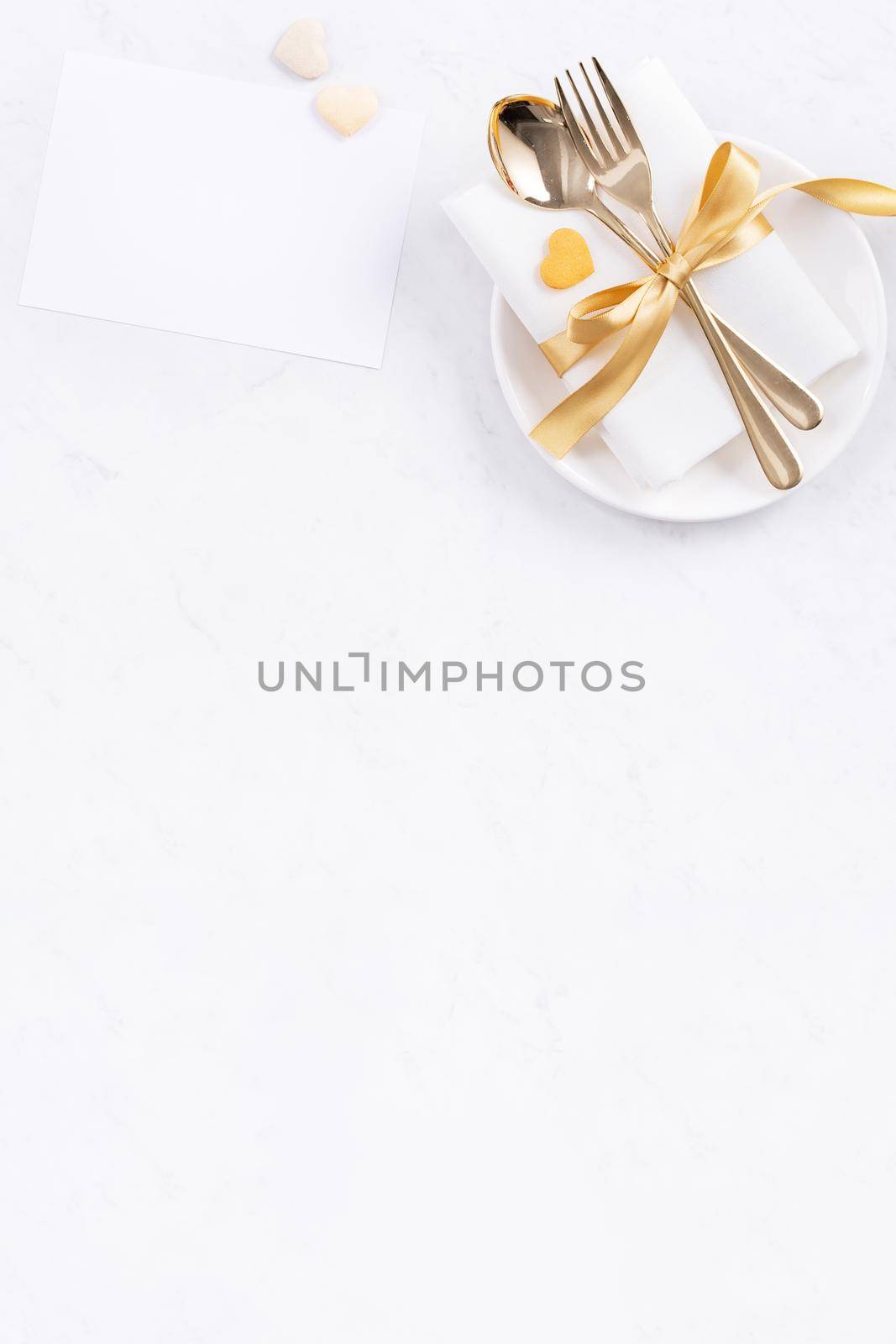 Valentine's Day, Mother's Day, holiday dating meal, banquet design concept - White plate and golden ribbon on marble background, top view, flat lay.