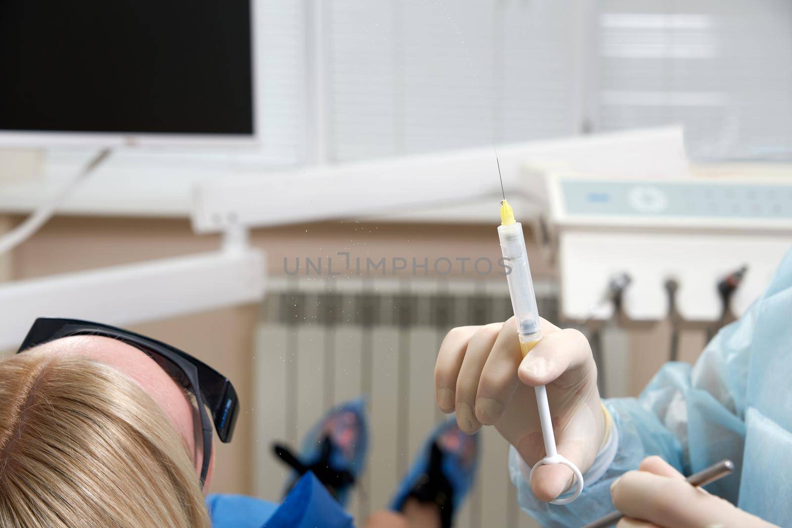 Hand of dentist holding dental syringe by Mariakray