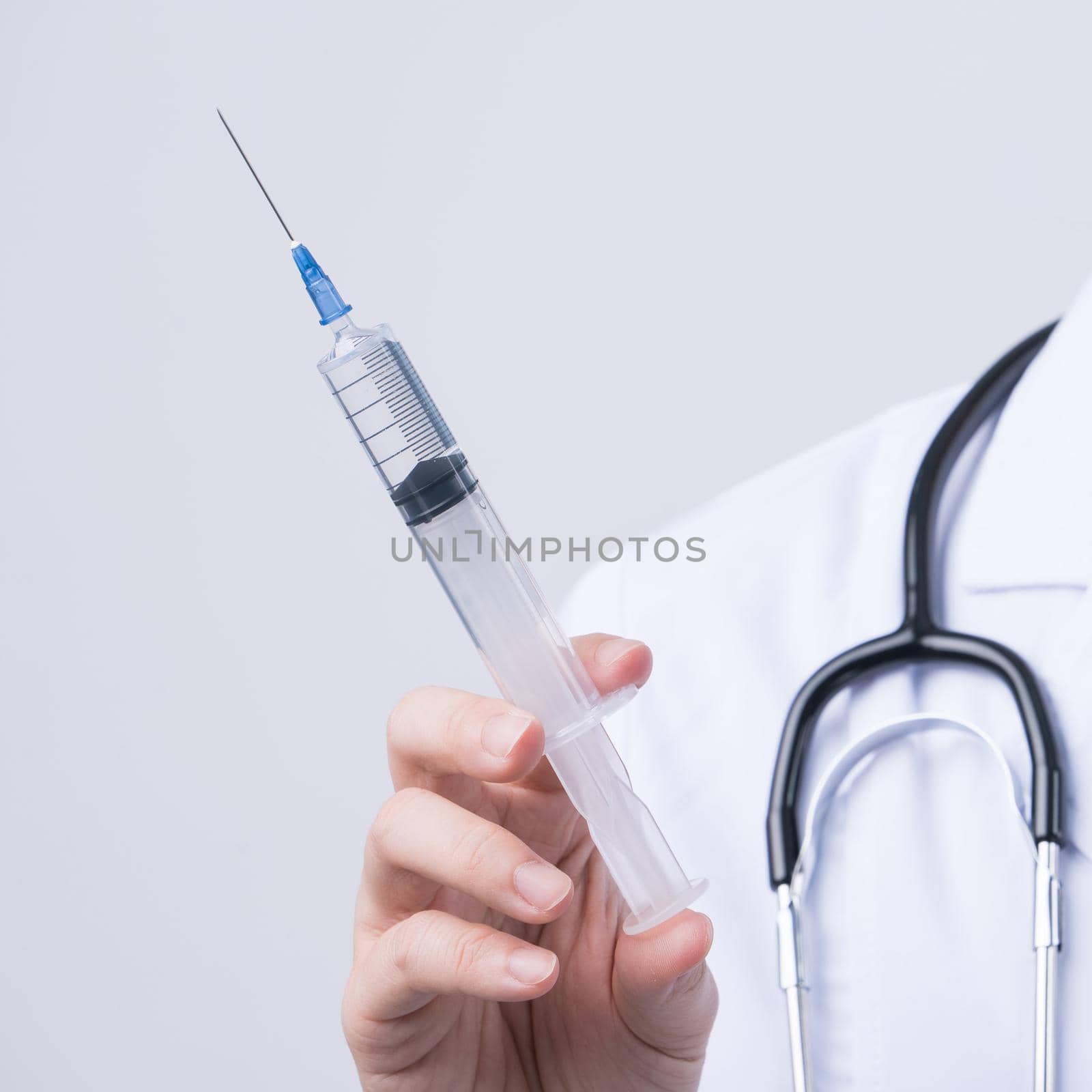 Doctor holding syringe with face mask, concept of young female physican injects coronavirus, COVID-19 vaccine on white background, close up, copy space