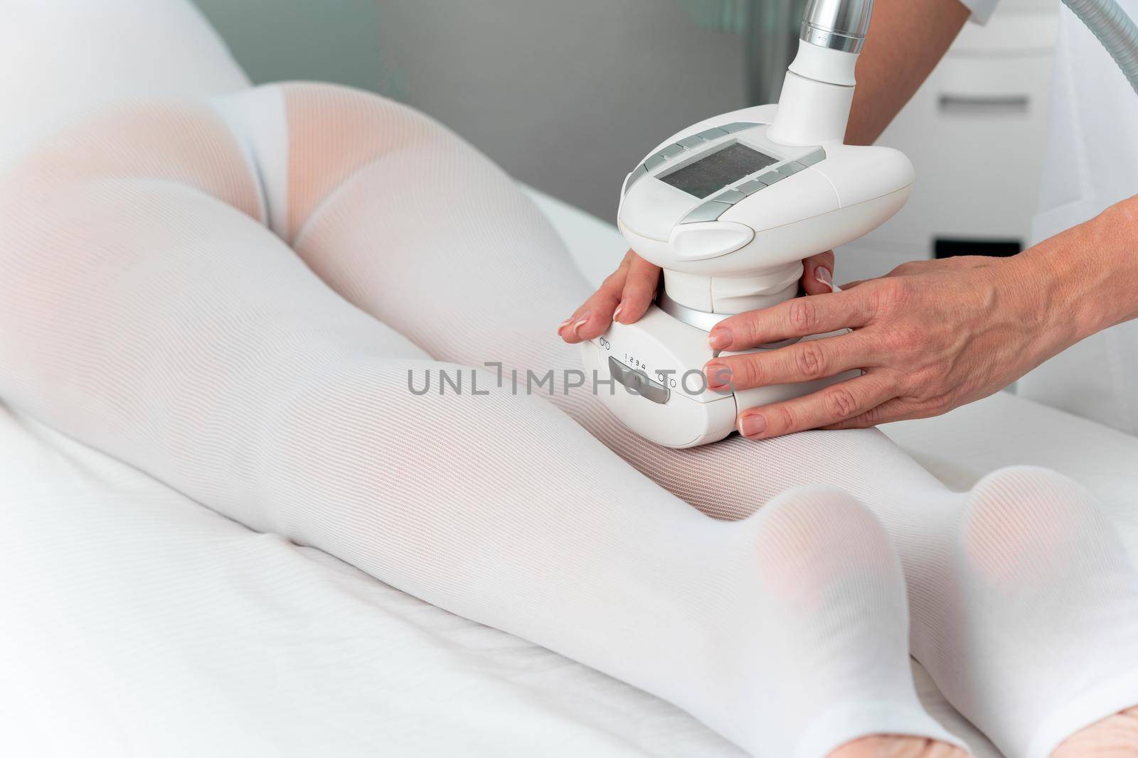 Woman in special white suit getting anti cellulite massage in a spa salon. LPG, and body contouring treatment in clinic