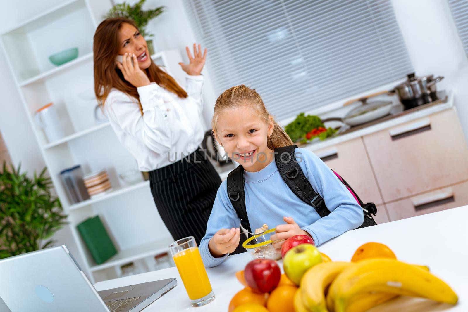 A little girl prepares a breakfast while her overworked mother phoning, before she goes to the work. Mother is getting angry because of a stress.