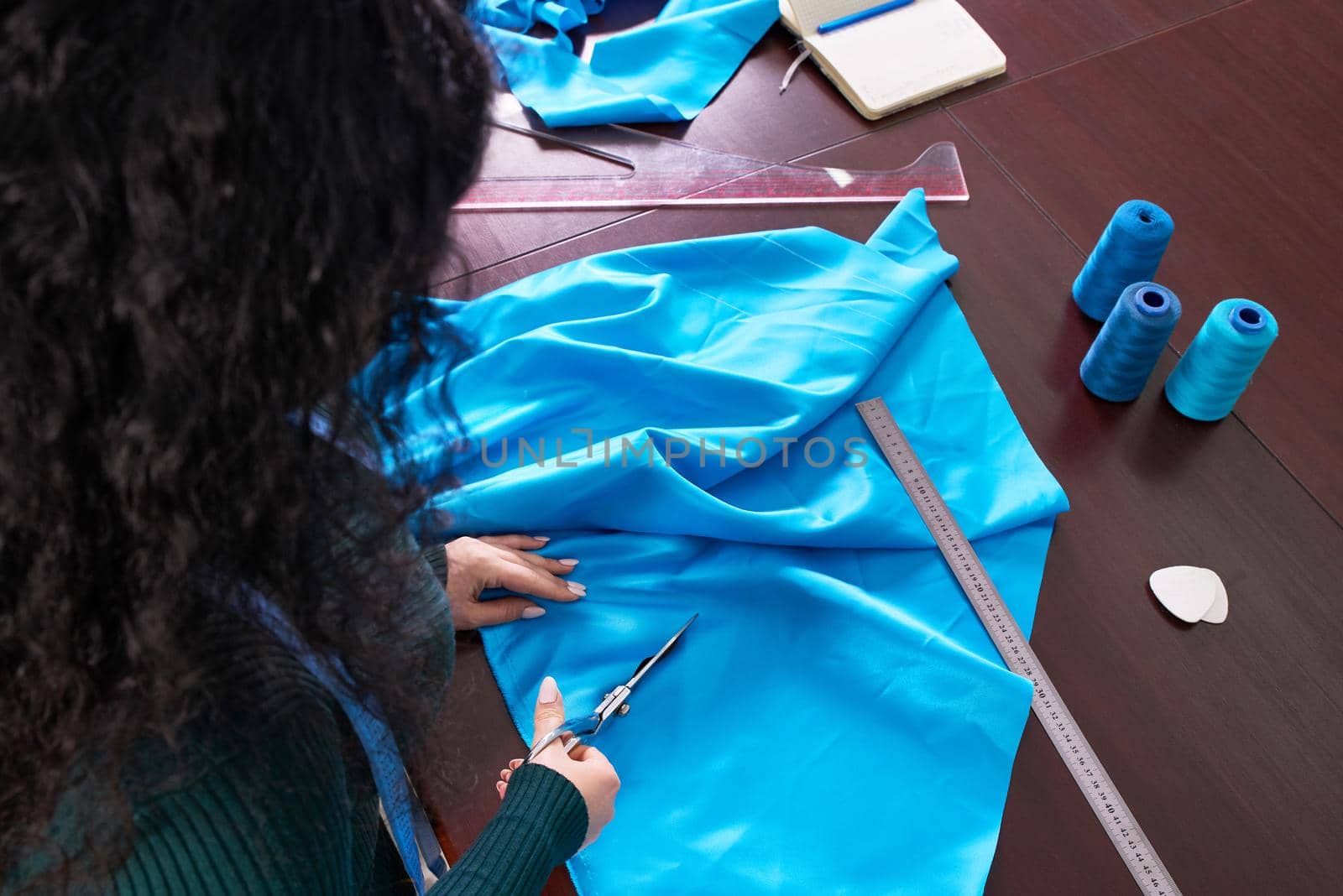 Dressmaker cutting fabric in atelier shop