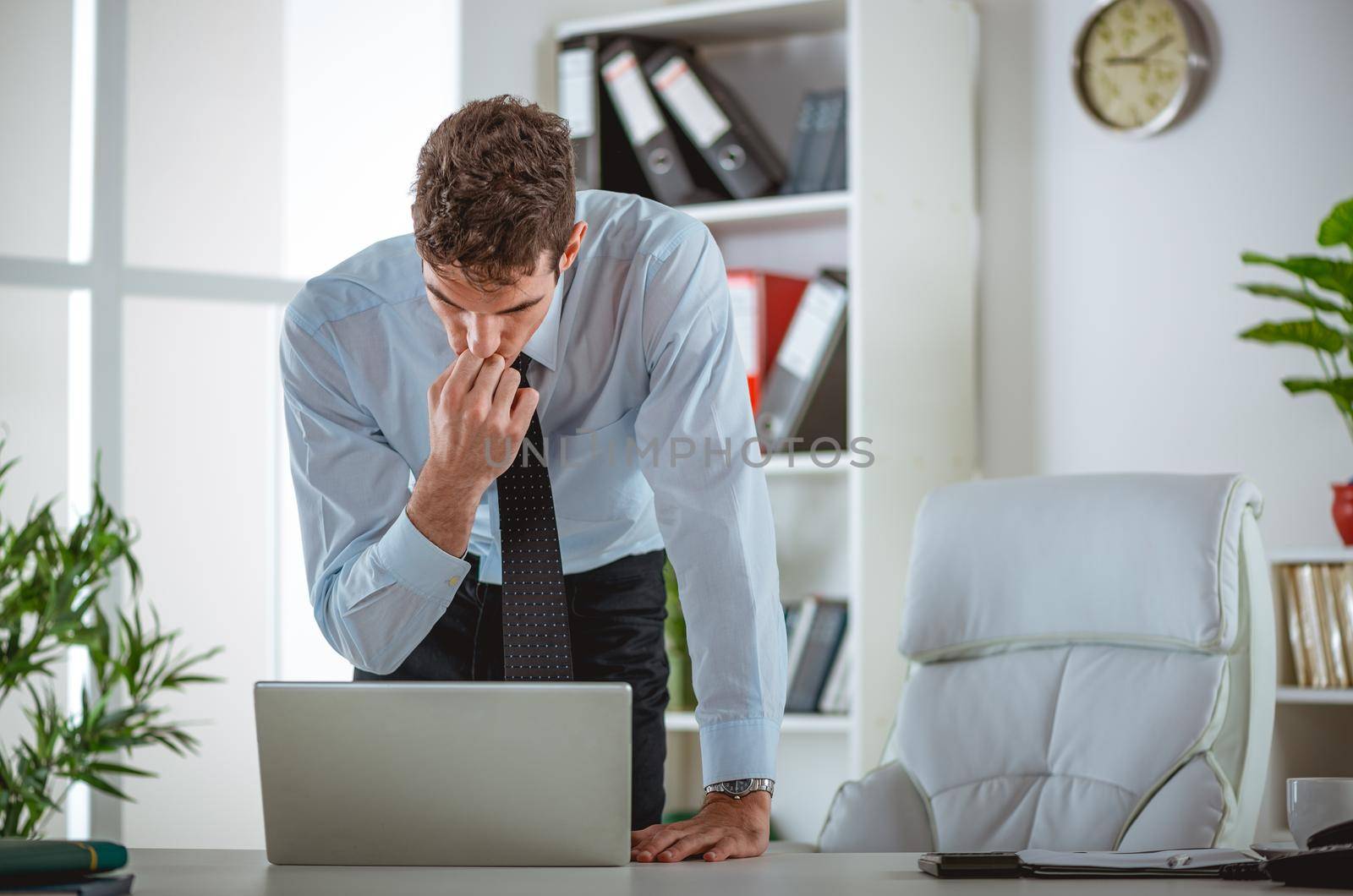 Executive male used laptop, looking at documents and accounts. He is unsure what to do with news he is writing at the screen.