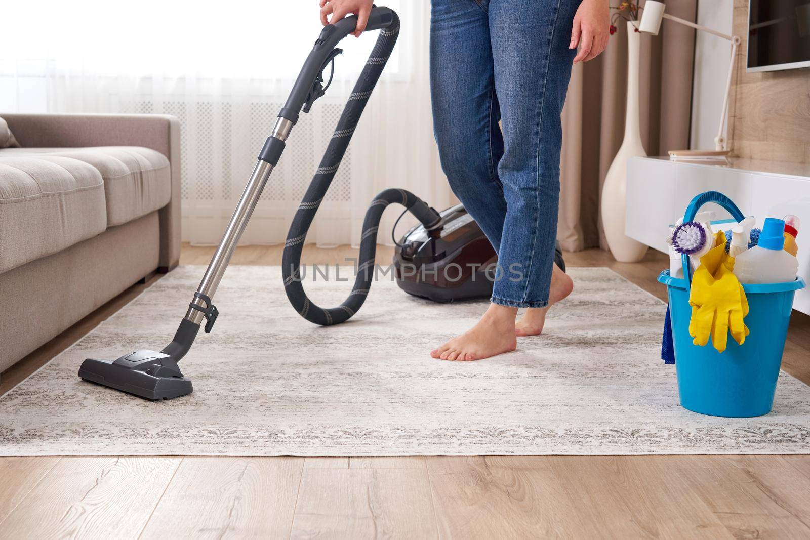 Woman cleaning the carpet with vacuum cleaner in the modern living room