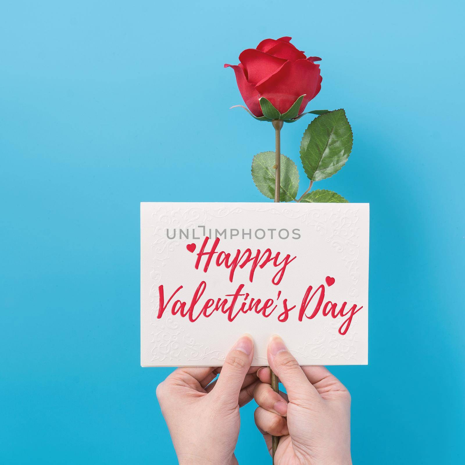 Valentine's Day gift card with greeting word design concept, woman sending gift on vibrant blue background, top view, overhead. by ROMIXIMAGE