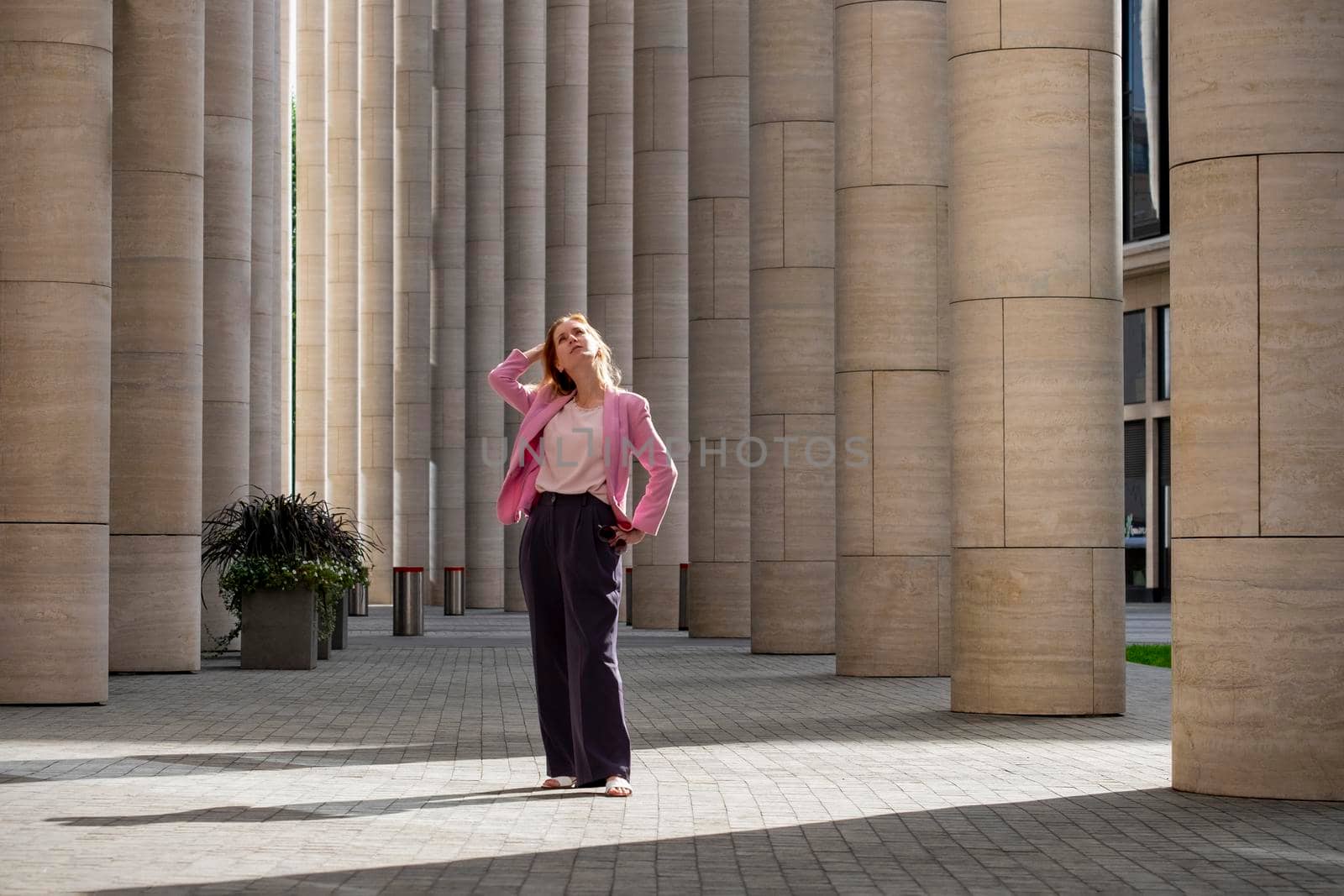 Young beautiful blonde millennial with long hair s stands and looks up by OlgaGubskaya