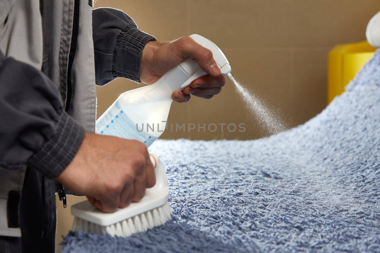 Man using chemical spray to remove stain from carpet in carpet cleaning service