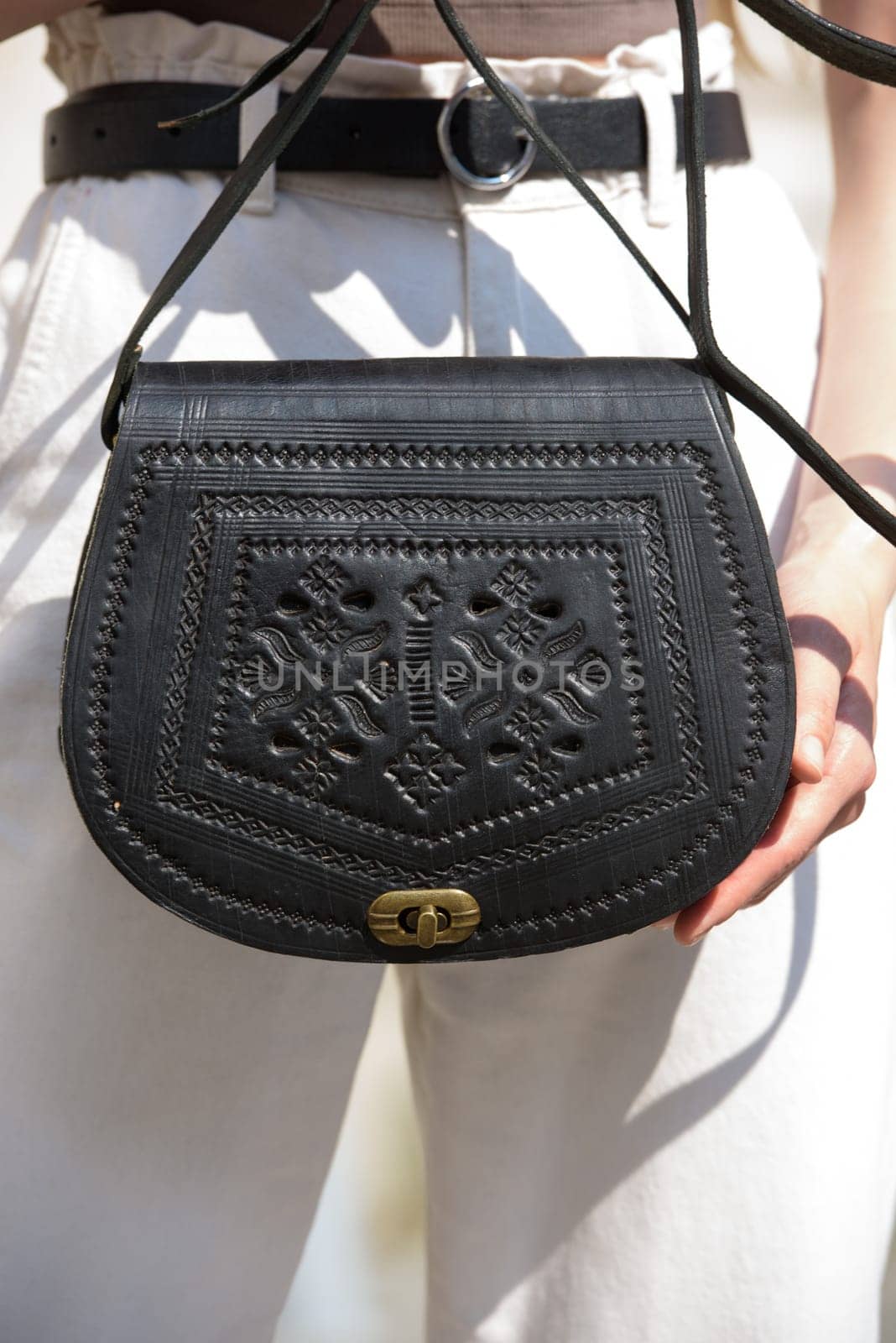 small black women's leather bag with a carved pattern. street photo