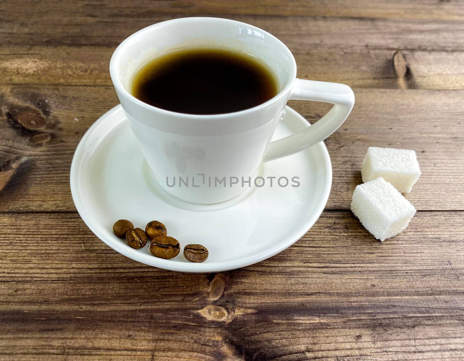 Coffee in a cup and sugar on the table. Coffee in a cup with saucers and sugar on a wooden table.