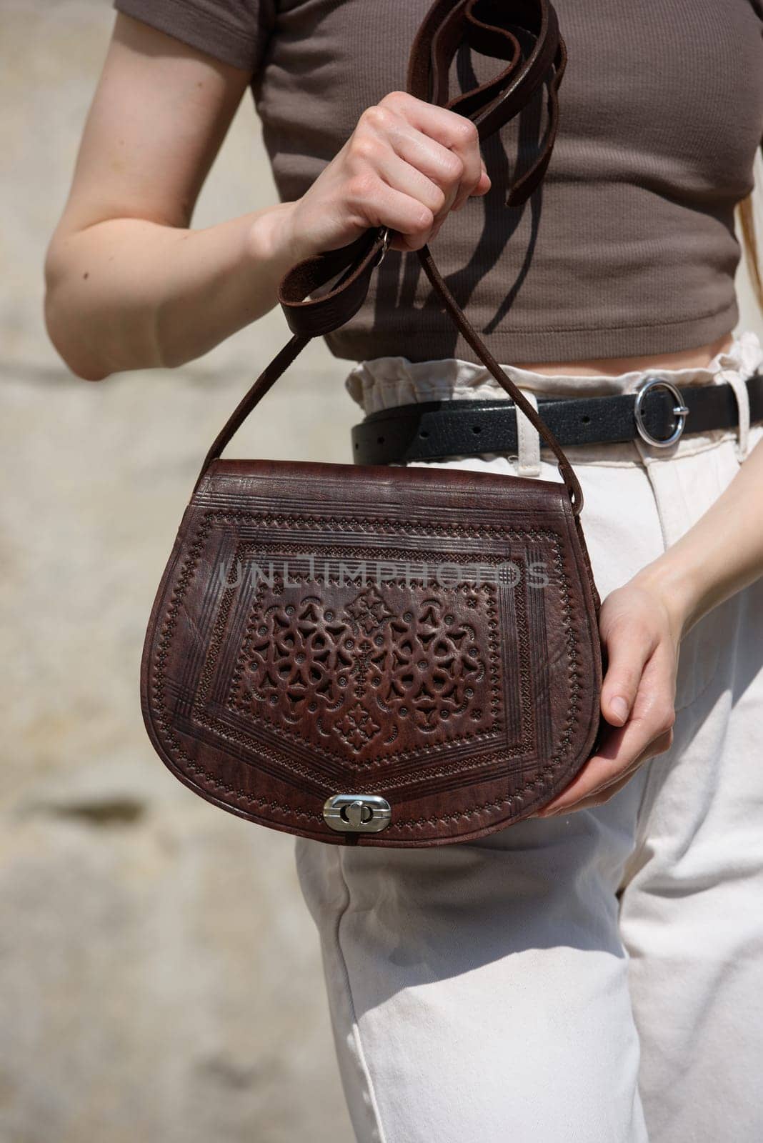 small brown women's leather bag with a carved pattern. street photo