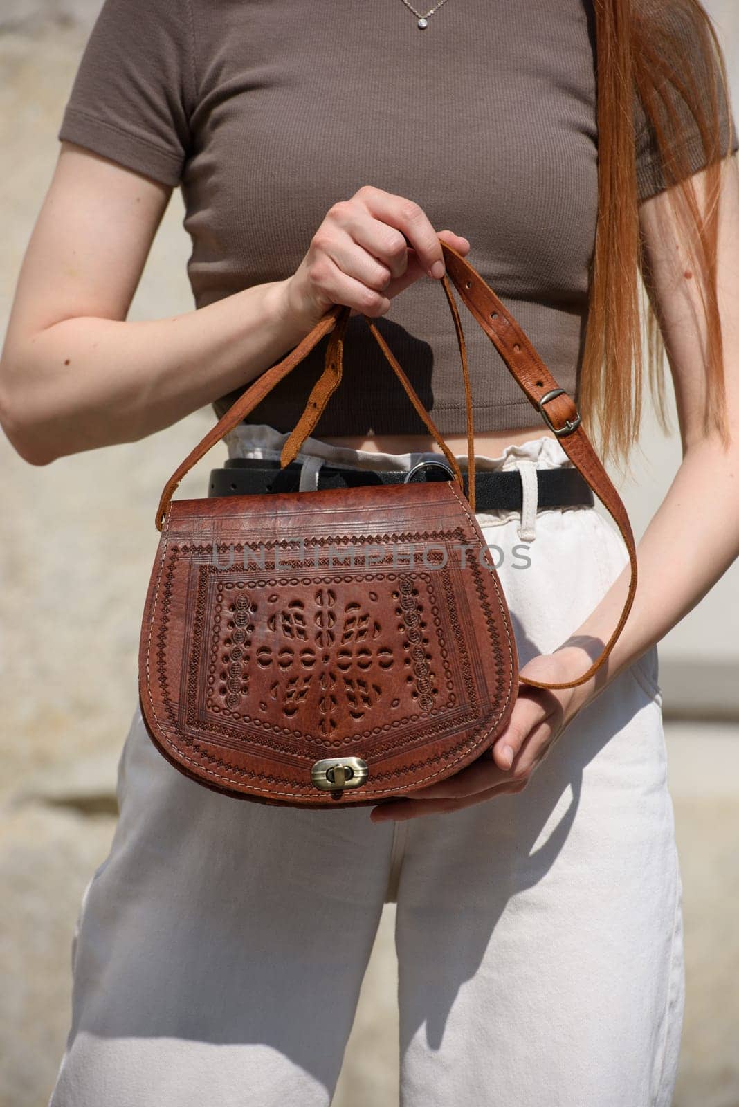 small brown women's leather bag with a carved pattern. street photo