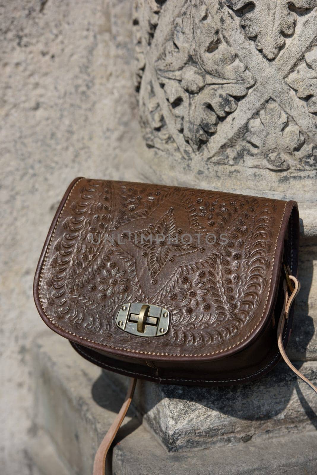 small brown women's leather bag with a carved pattern. street photo