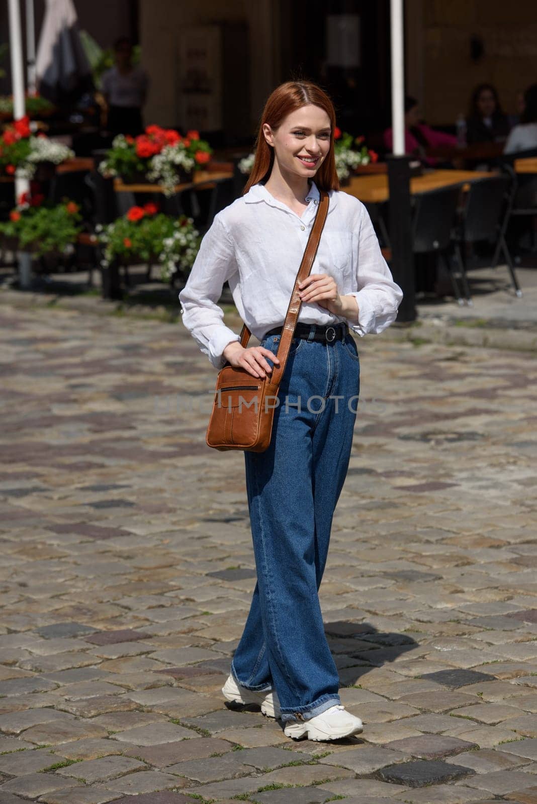 photo of a woman with a small yellow leather bag. the girl is dressed in jeans, a white blouse and sneakers