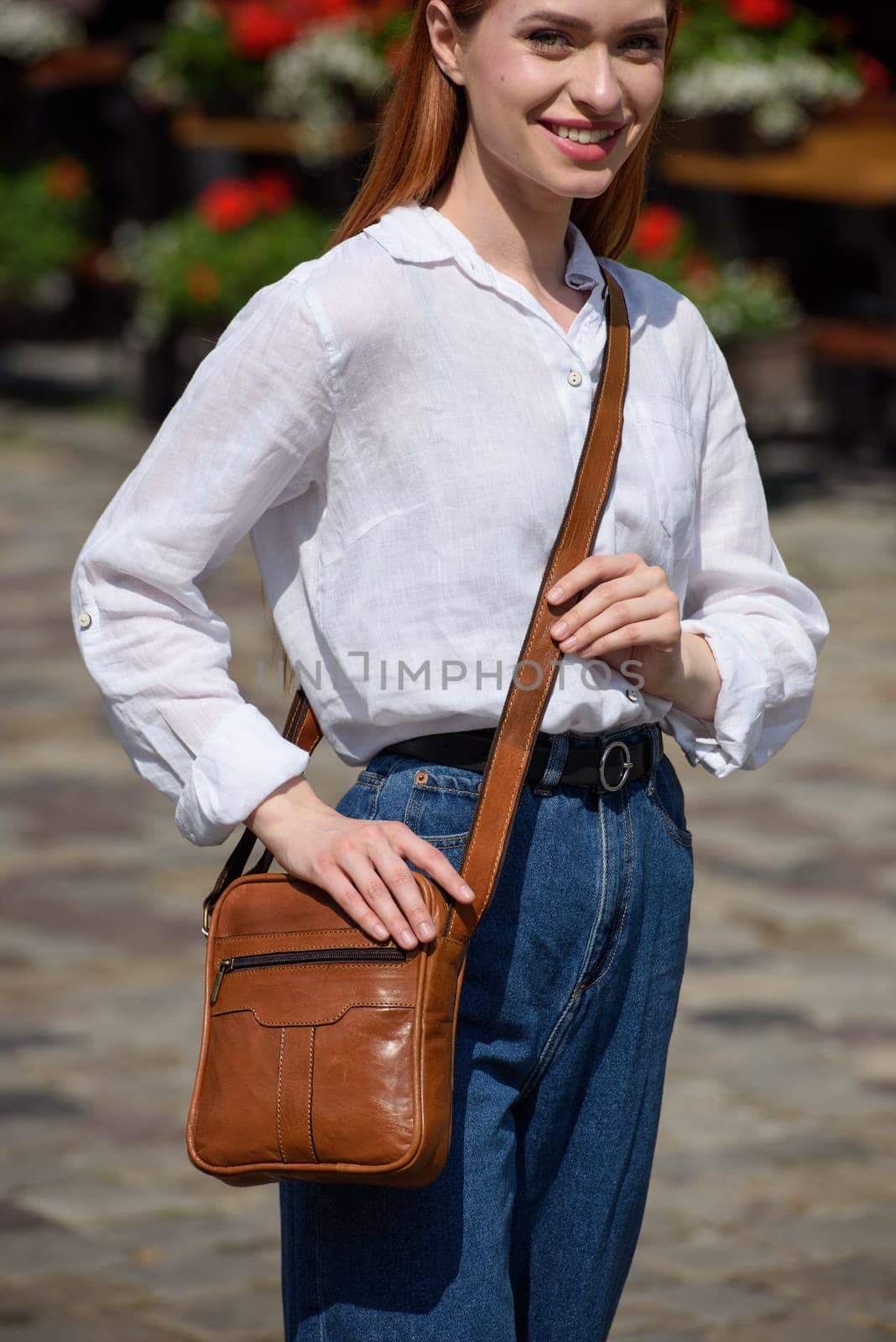 photo of a woman with a small yellow leather bag. the girl is dressed in jeans and white blouse