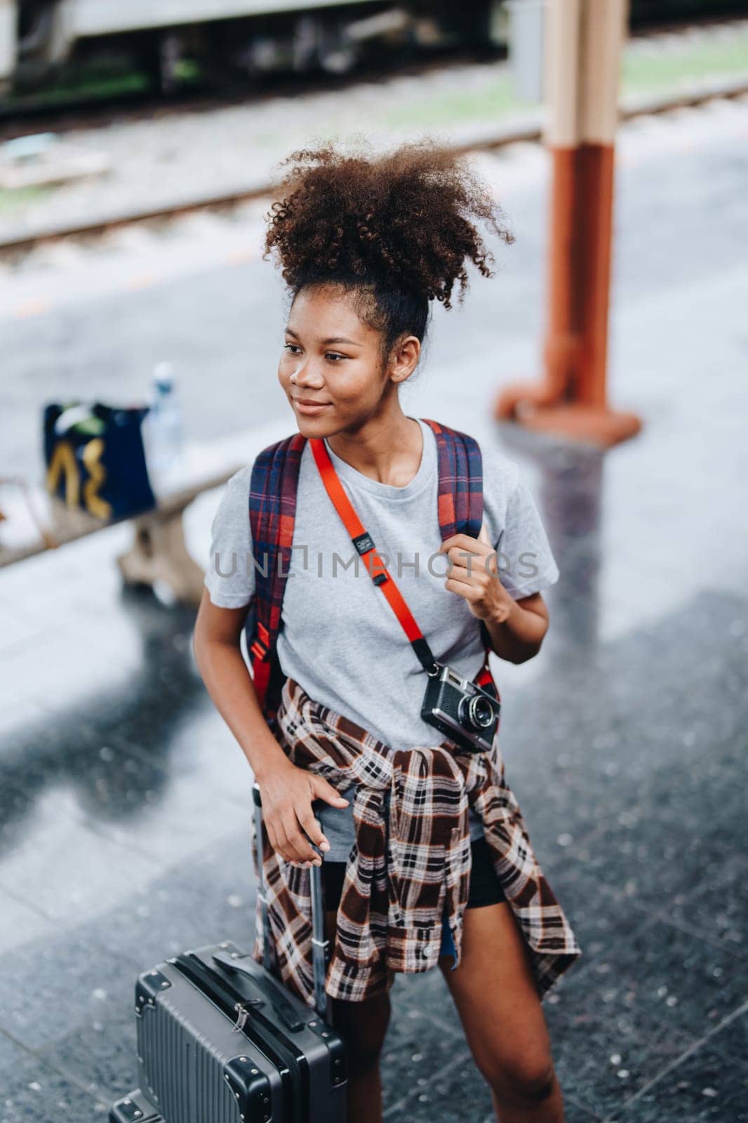 Tourists african american are showing happy expressions while waiting for their journey in the train station. by Manastrong