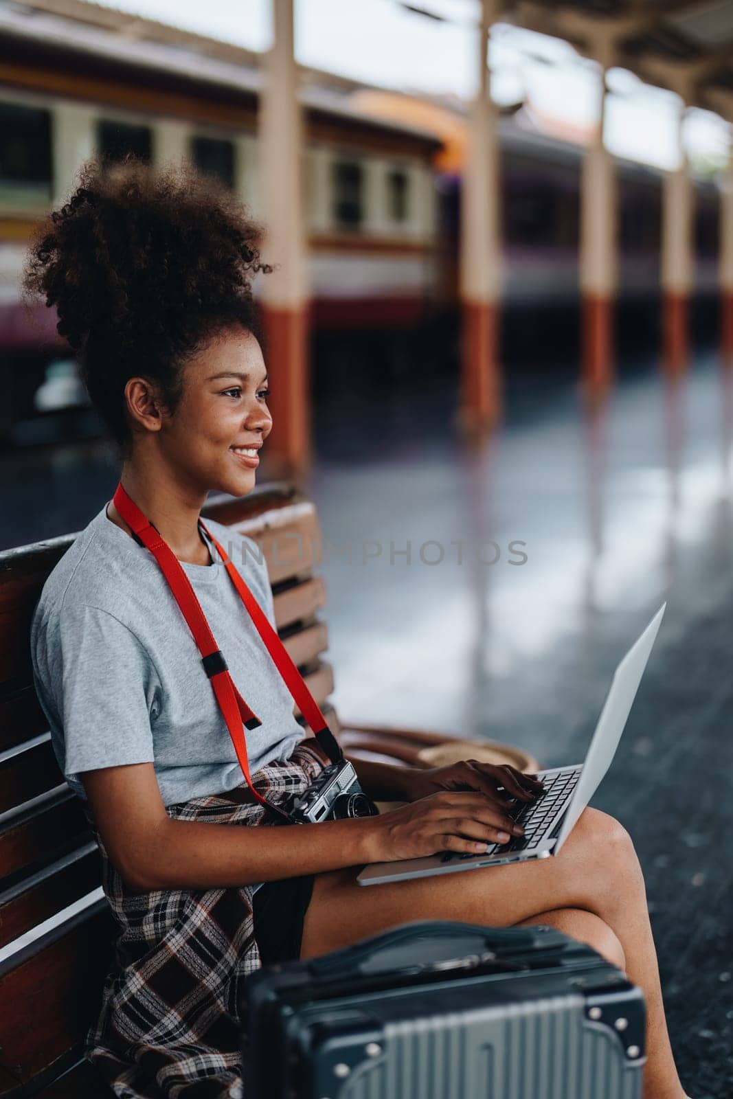 Asian teenage girl african american traveling using computer laptop while waiting for a train at a station